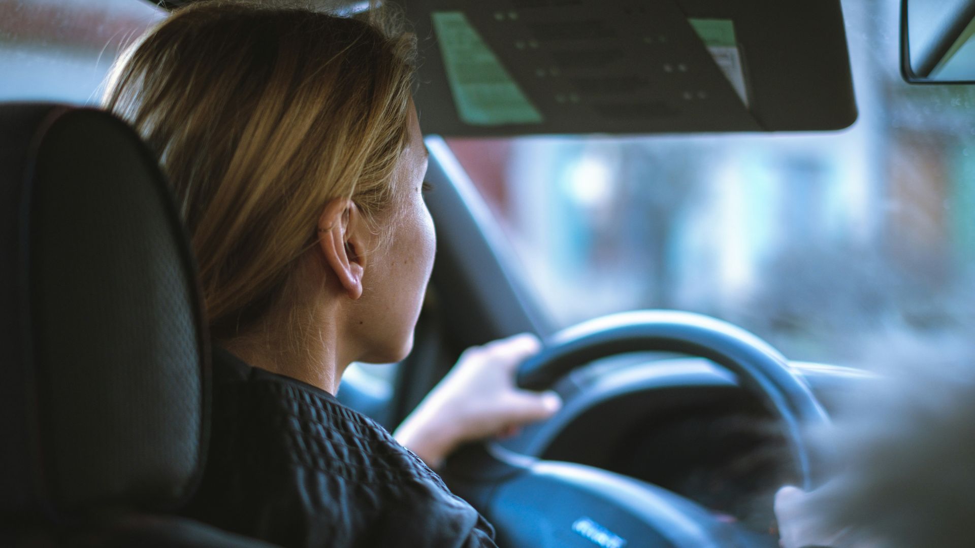 a woman sitting in a car with a steering wheel