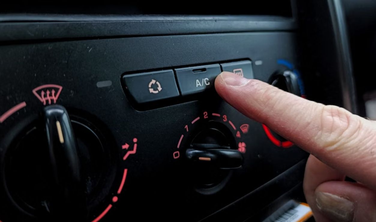 Close-up of a person adjusting a car's air conditioning system inside a vehicle cabin