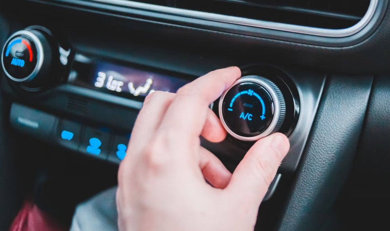 Close-up of a hand adjusting the air conditioning settings on a modern car dashboard
