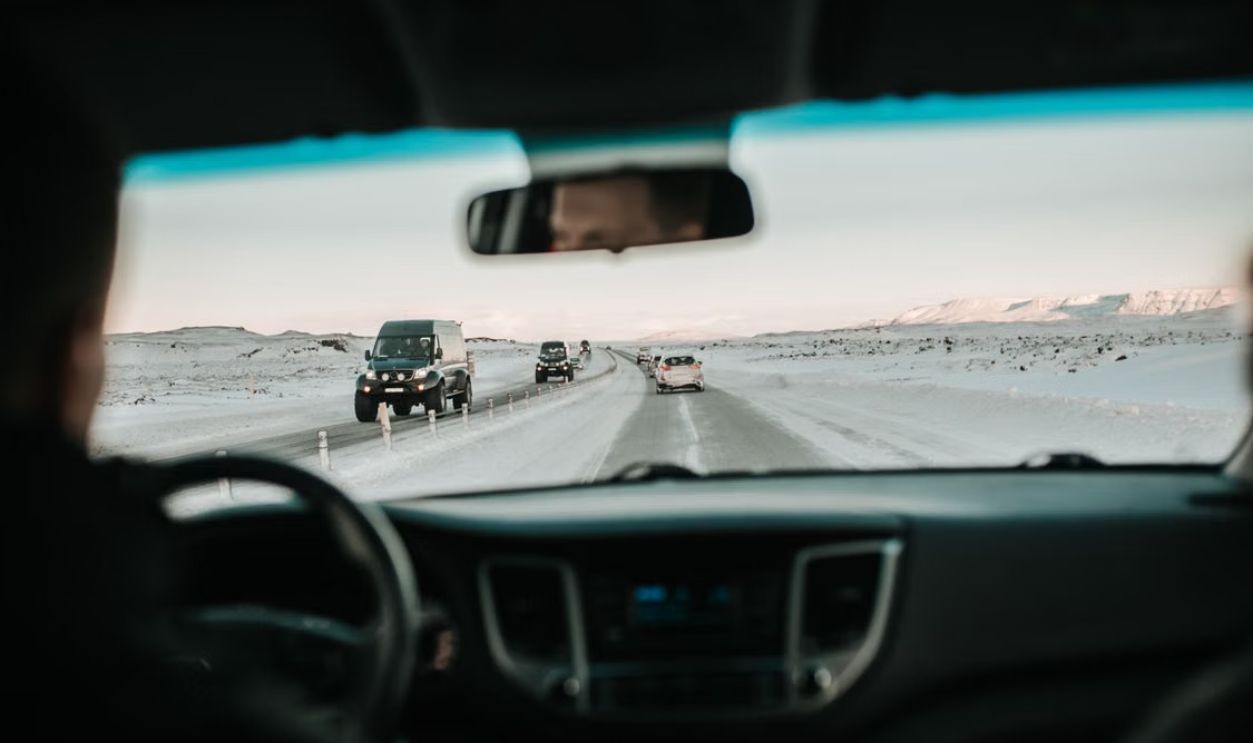 View from inside a car driving on a snowy road through a picturesque winter landscape