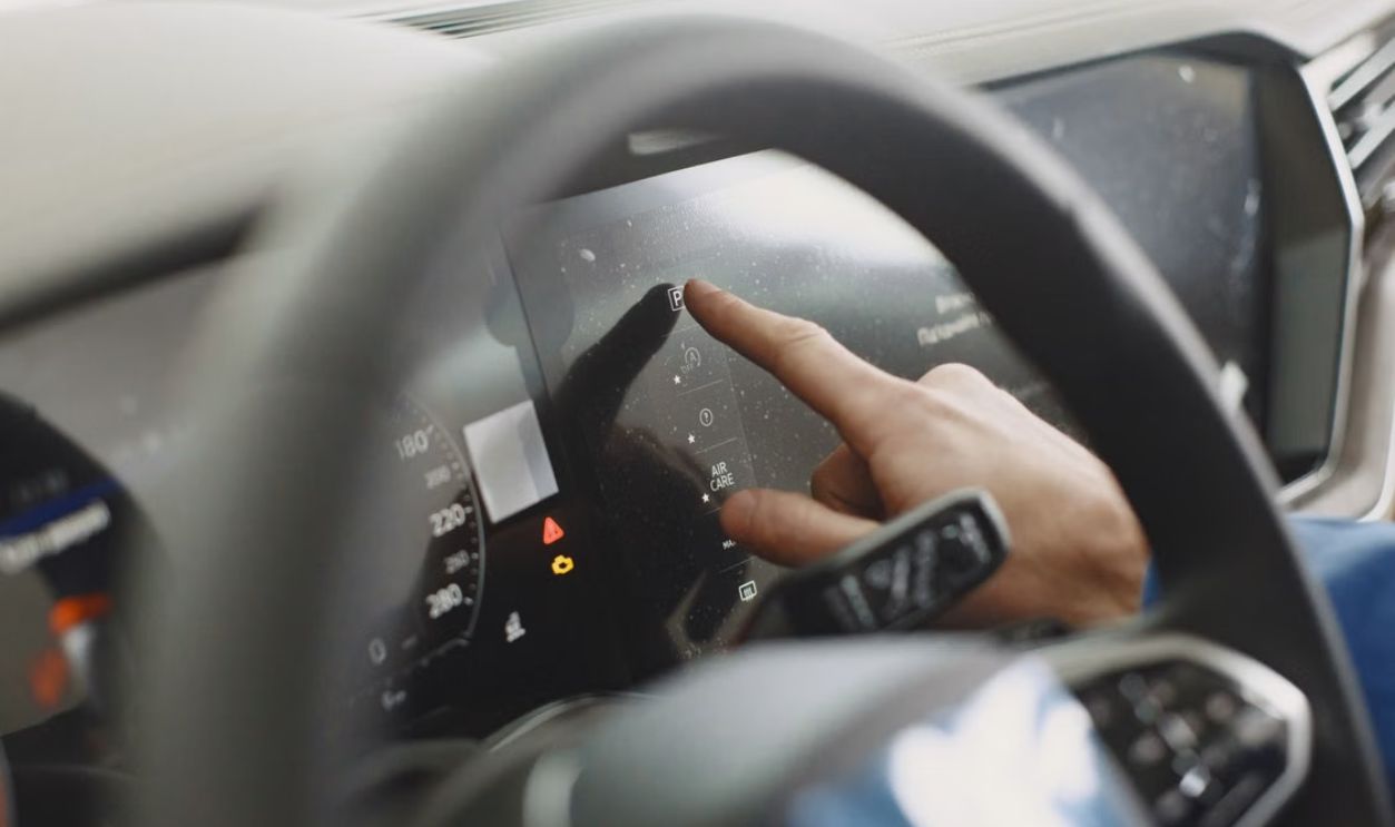 Close-up of a hand interacting with a car's digital dashboard. Modern technology and driving interface