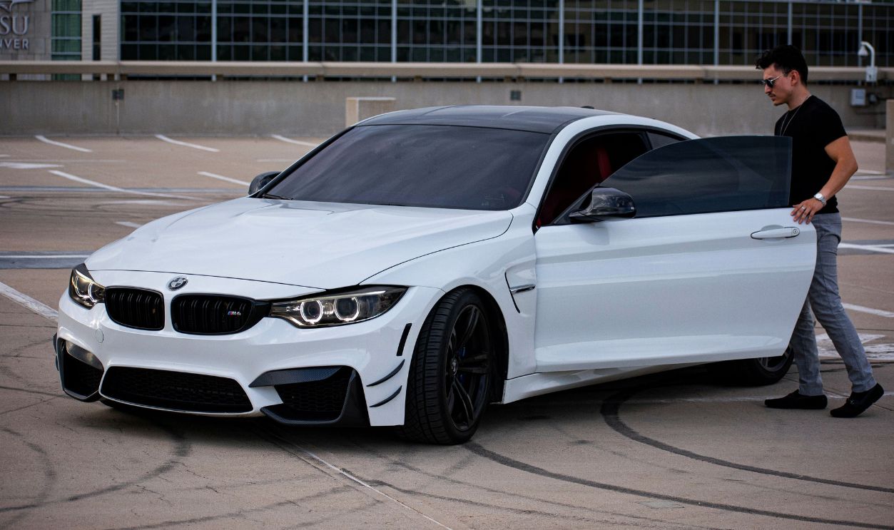 Man exiting luxury white sports car in urban rooftop parking area