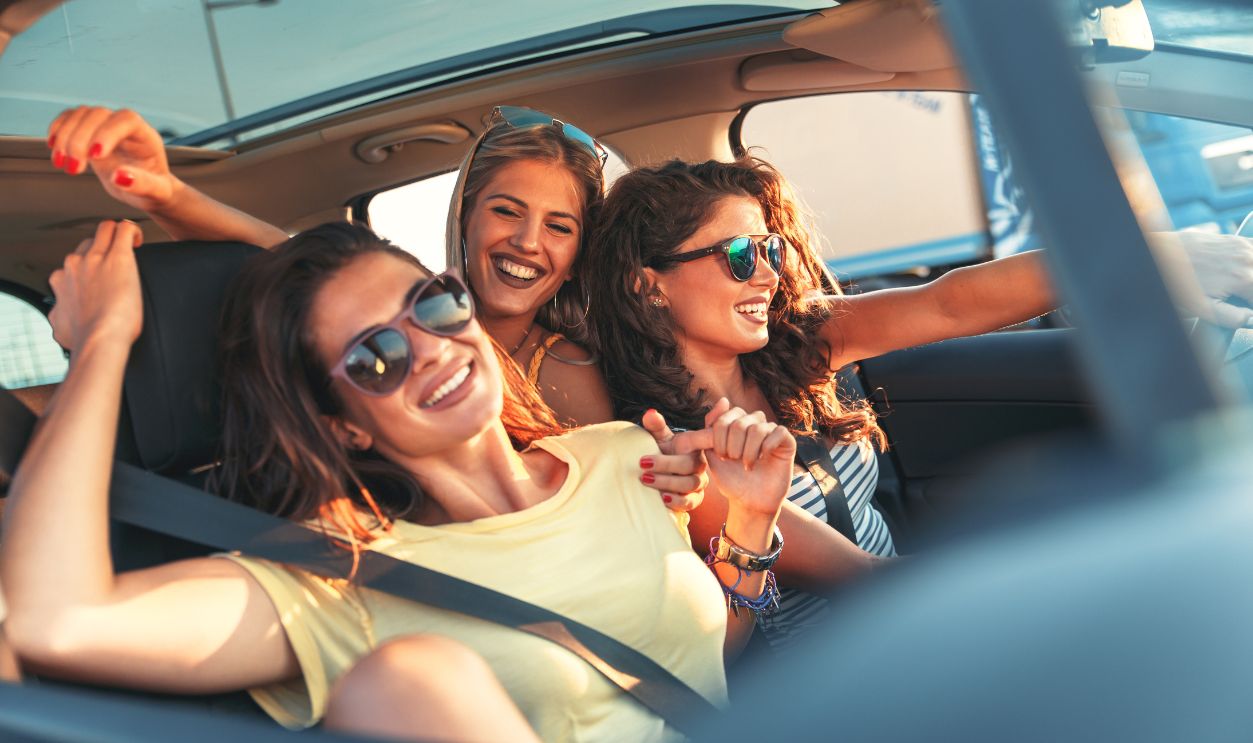 Three female friends enjoying traveling at vacation in the car.