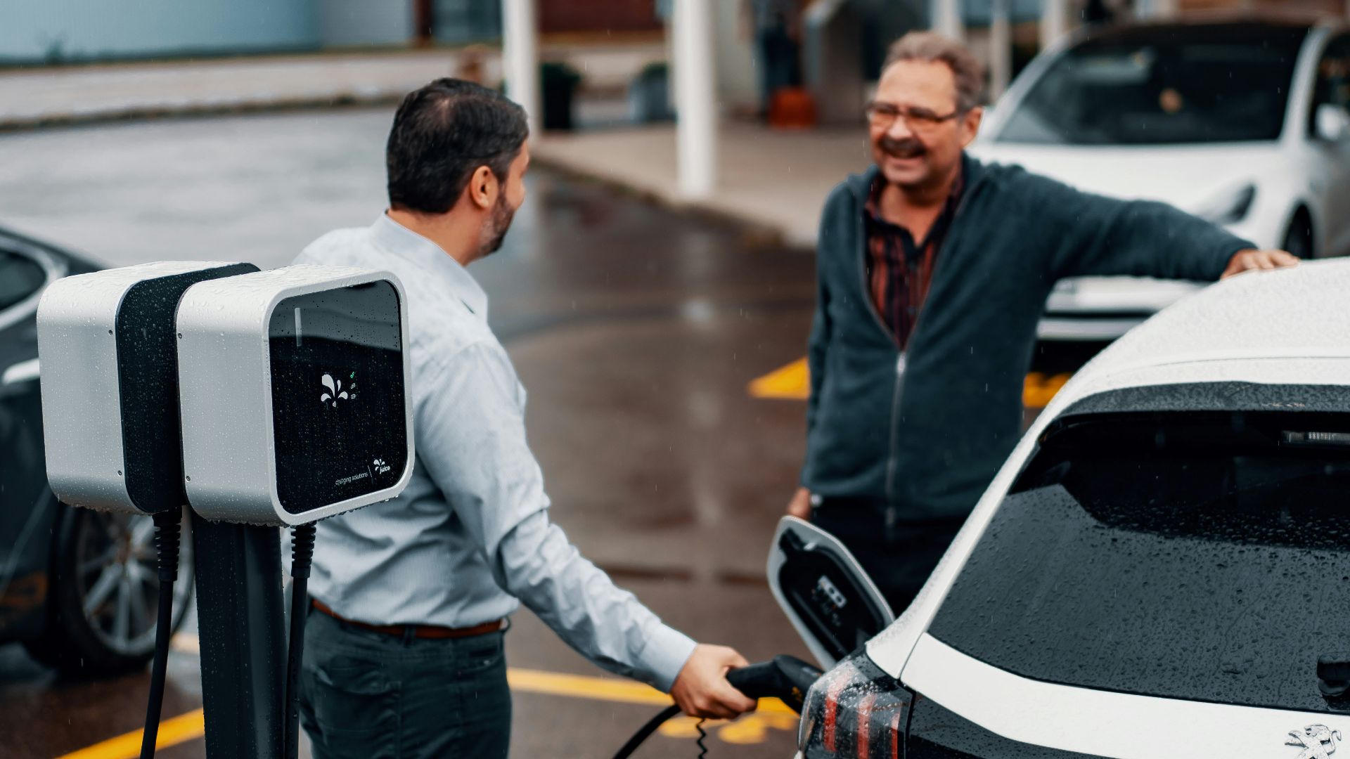 a couple of men standing next to a white car