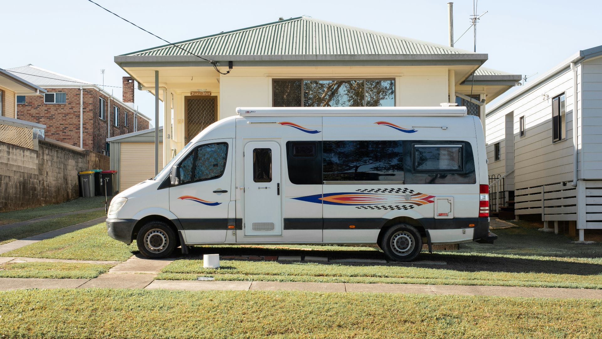 White camper van parked on lawn in front of house