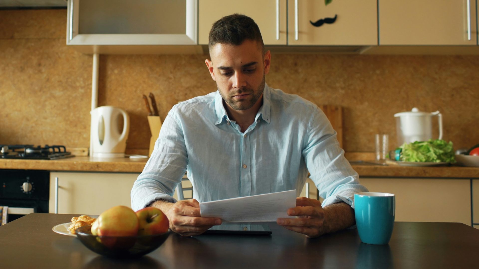 Man reading document at kitchen table with coffee