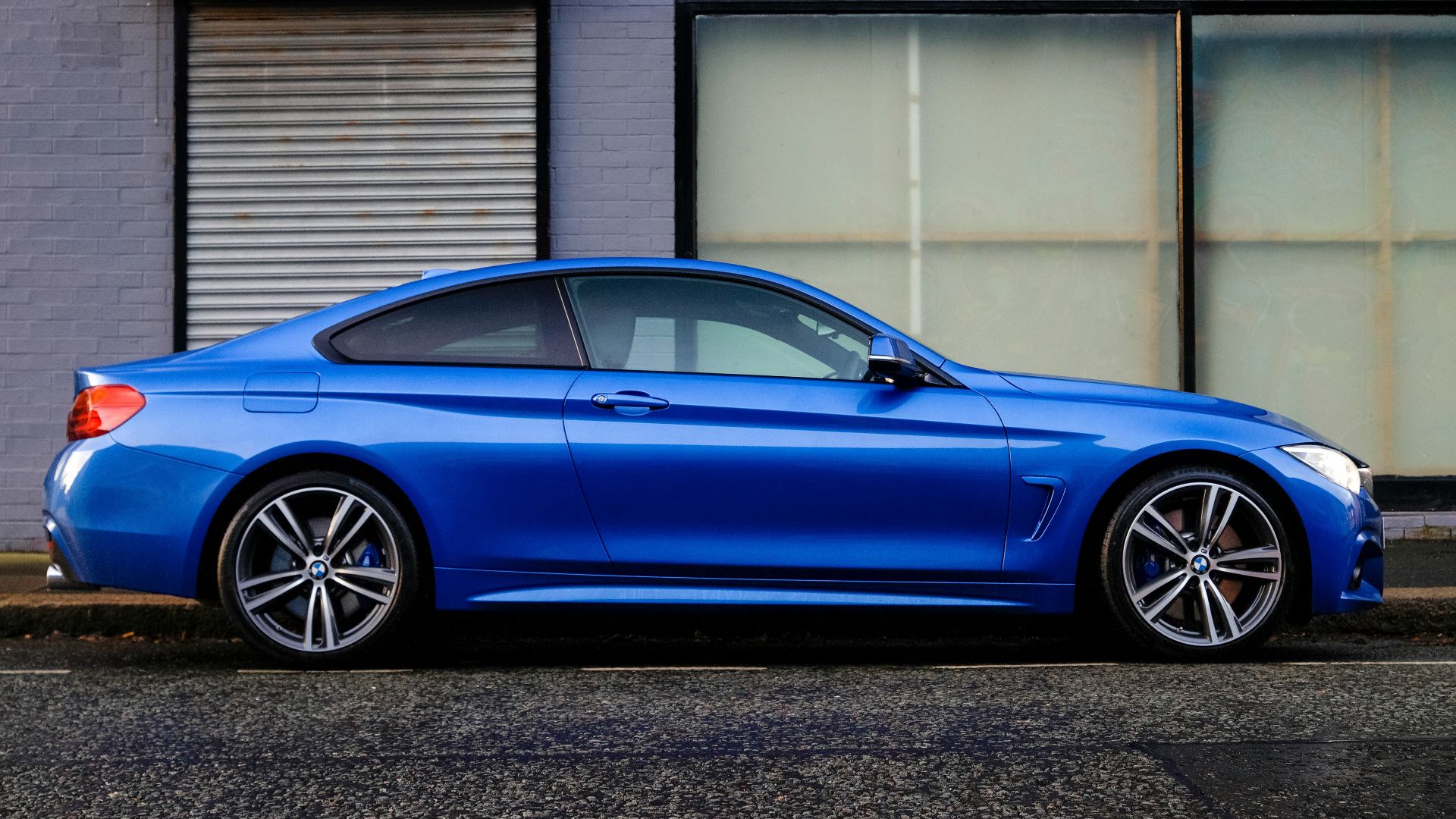 blue coupe beside gray house