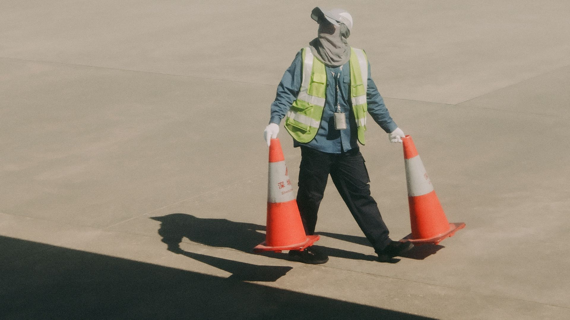 Worker with traffic cones near airplane wing