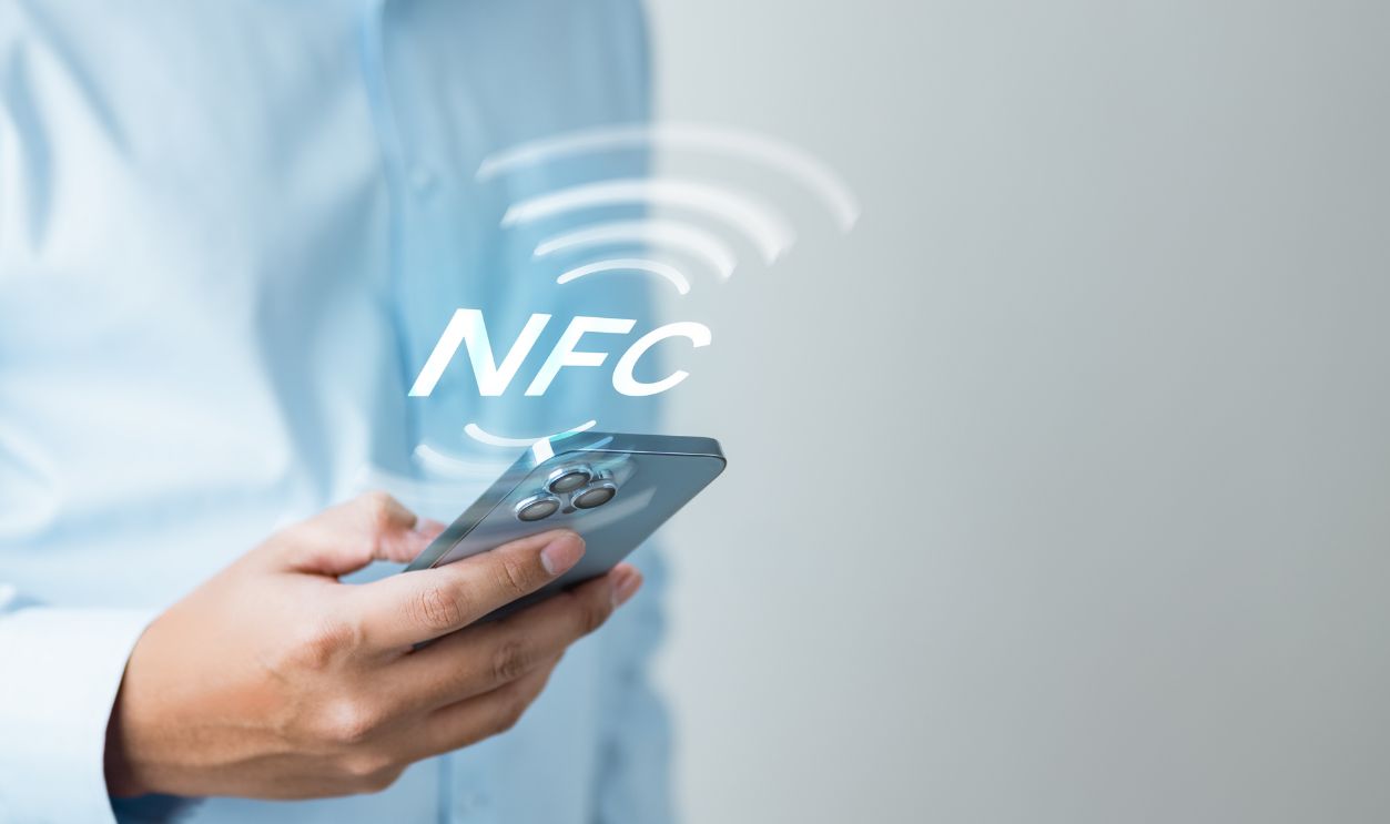 Shutterstock - 2692025279 - A person using NFC technology on a smartphone for contactless payment, representing mobile wallet, cashless transactions, and digital convenience.