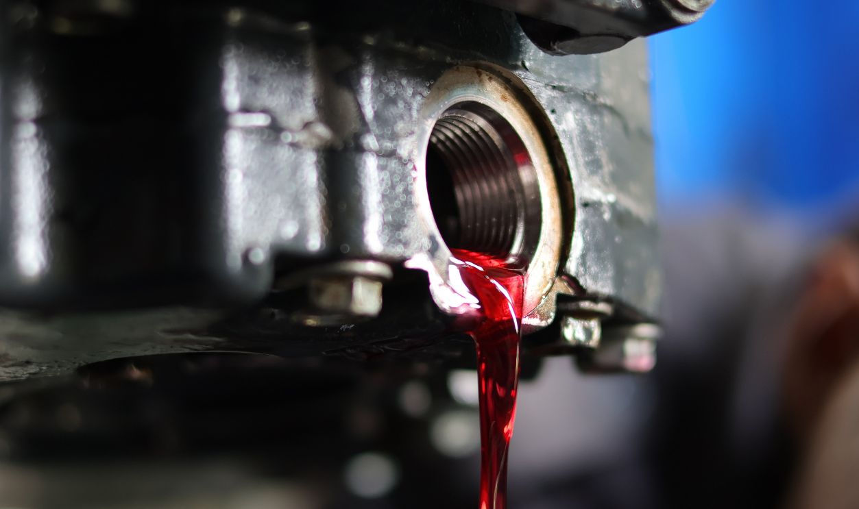 Auto mechanic loosen automatic transmission oil drain plug ,then let the old used automatic transmission oil flow out of the transmission oil pan.