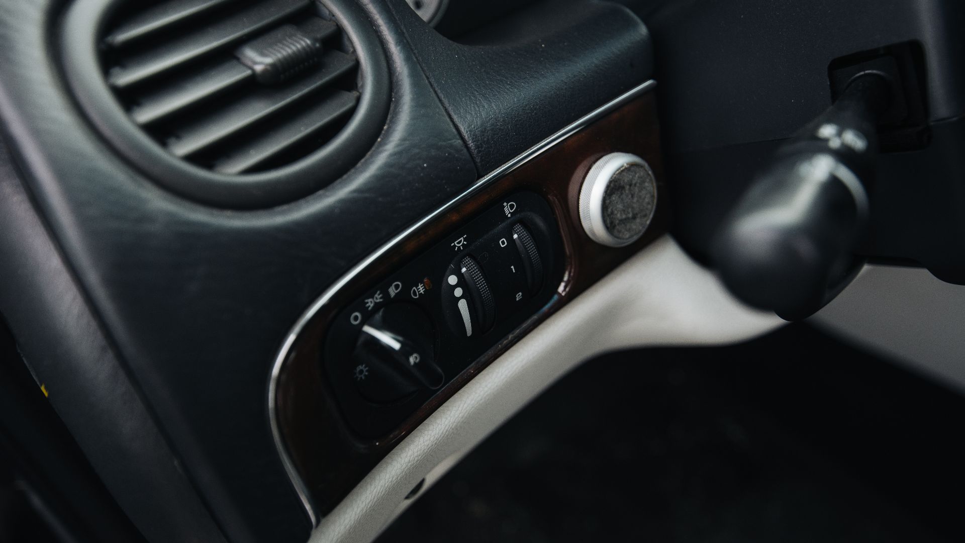 Controls located on the driver's side of a car manage air conditioning, lights, and other functions. The dashboard has buttons and knobs that help the driver while driving.