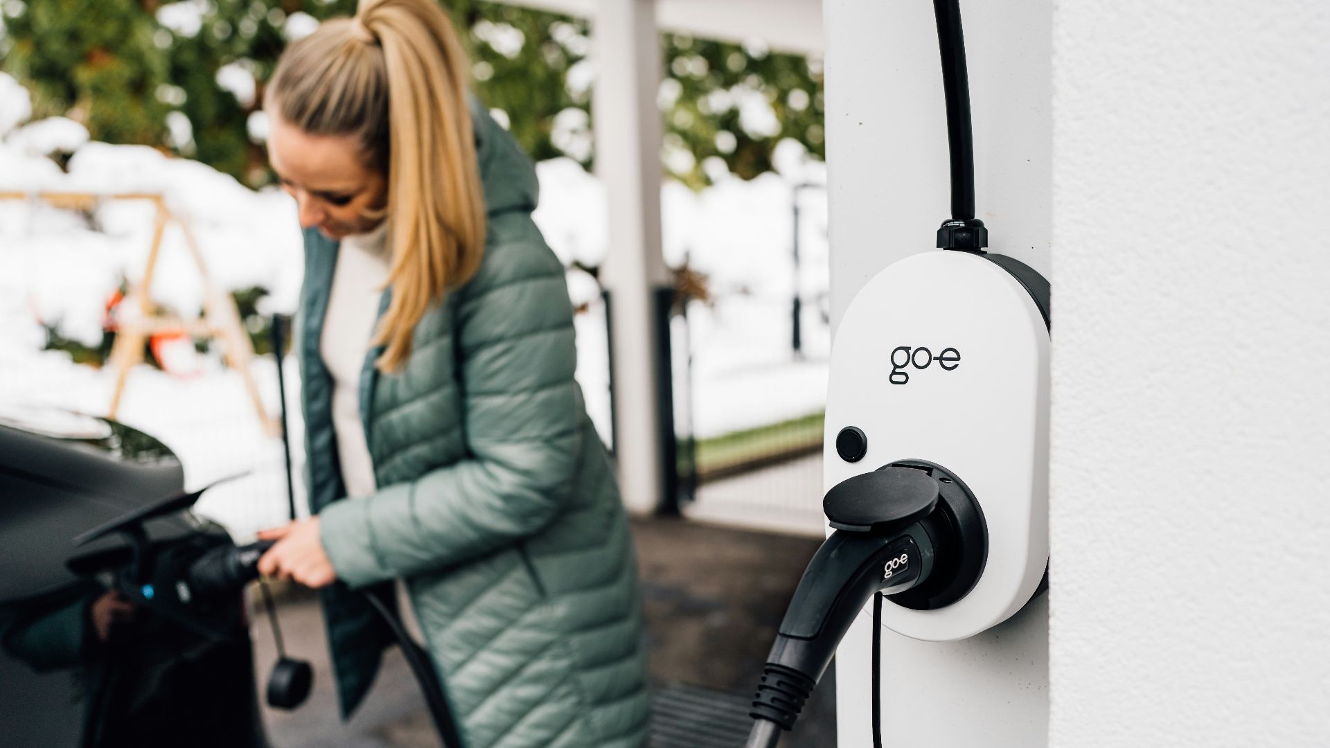 Woman plugs in an electric car to charge