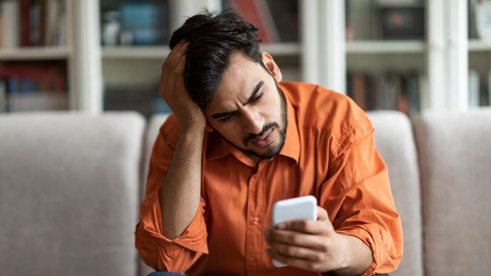 Shocked man in orange shirt looking at his phone