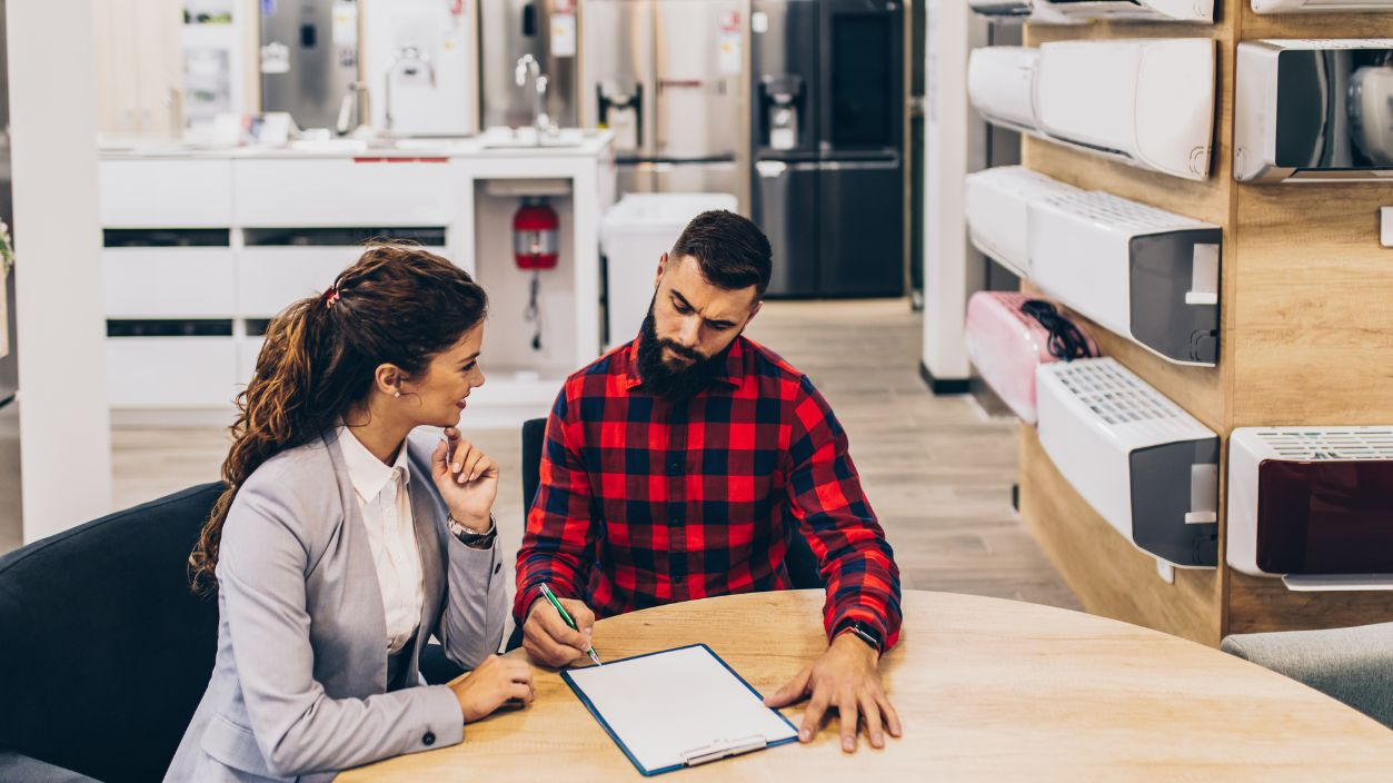 Shutterstock-1531973942, Young man with saleswoman in large modern household appliances store signing contract.