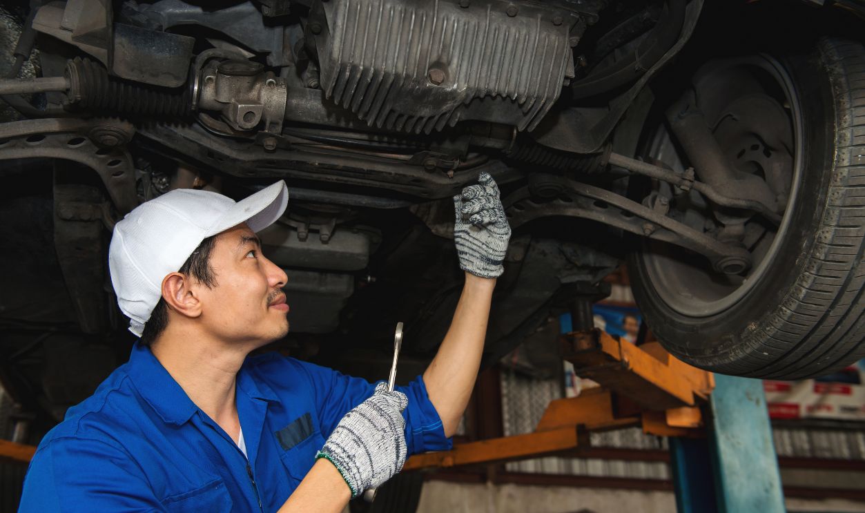 Asian mechanic looking under the car to repair the engine,japanese mechanic portrait style, mechanic maintenance working under car