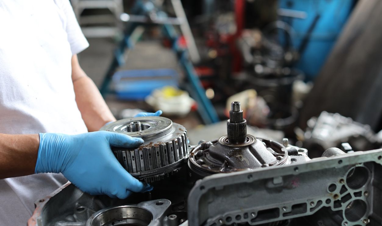 Man technician car mechanic hamds in half uniform checking maintenance a car service at repair garage station. Worker holding wrench and fixing breakdown vehicle. Concept of car center repair service.