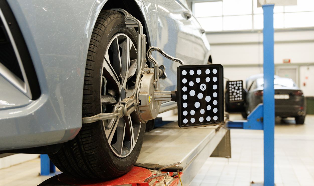 Shutterstock - 2452323001 - Car tire steering wheel balancing calibrate device for center adjust after tyre replace at car repair service center.
