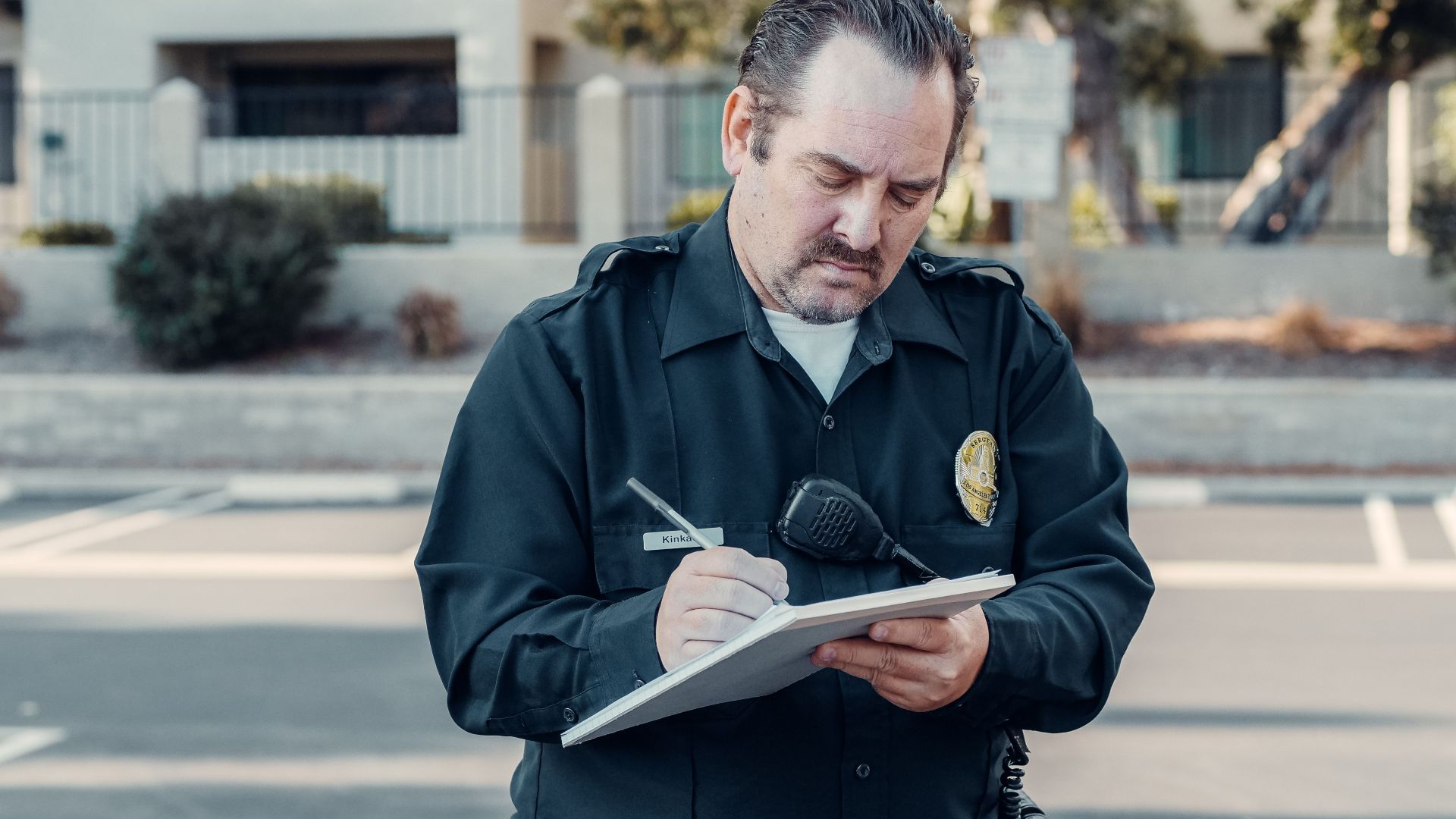 Police officer in uniform writing a ticket on a clipboard outdoors.