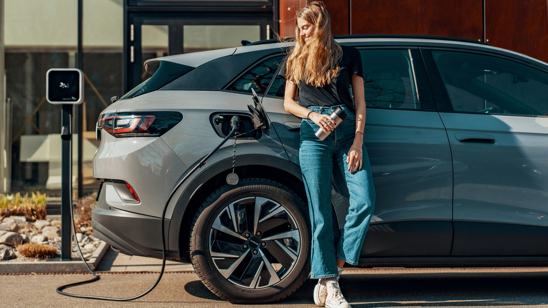 a woman standing next to a blue car