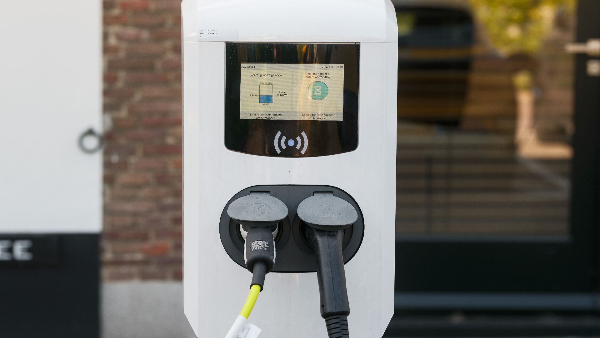 Close-up image of a modern electric vehicle charging station outdoors with two cables connected.