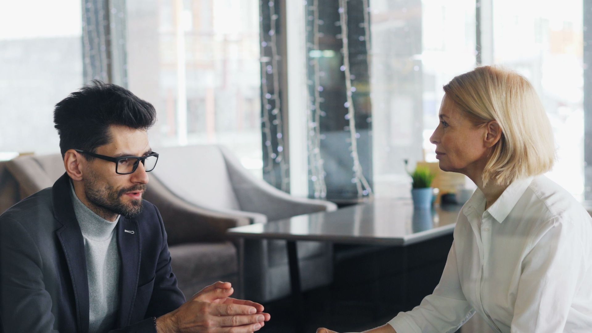 Businessman and businesswoman having a discussion over coffee in a stylish cafe setting.