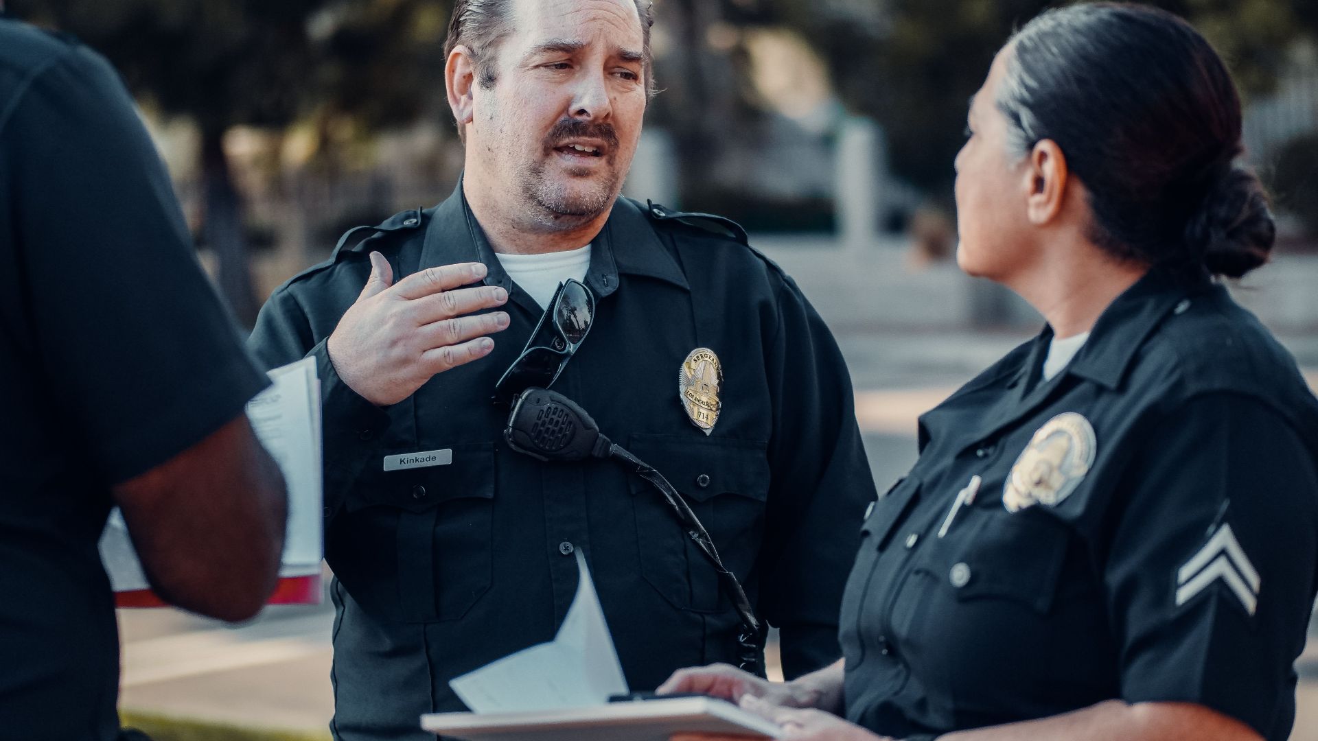 Three police officers engage in conversation outdoors, showcasing teamwork.