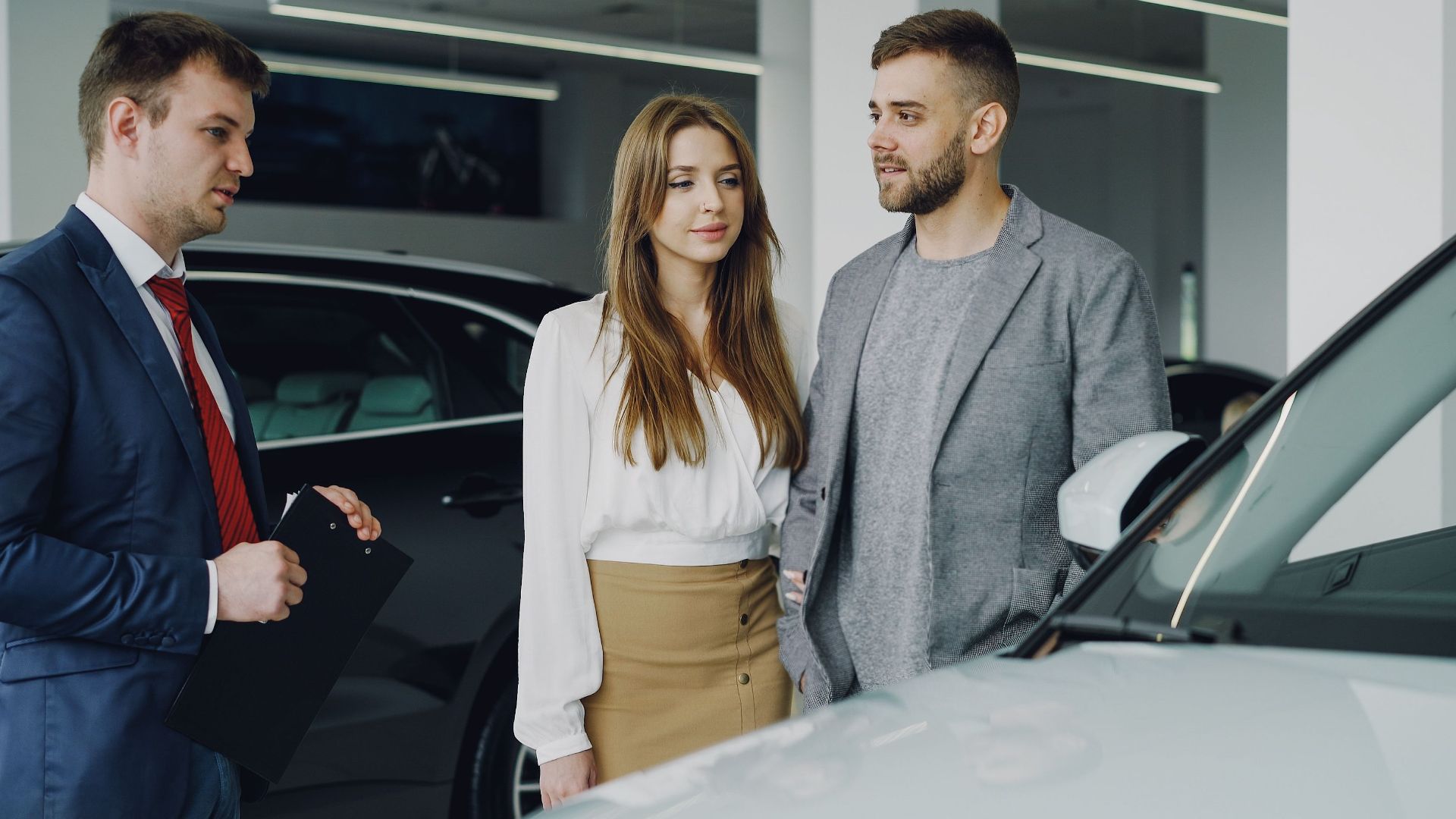 Couple discussing options with a car salesman inside a dealership.