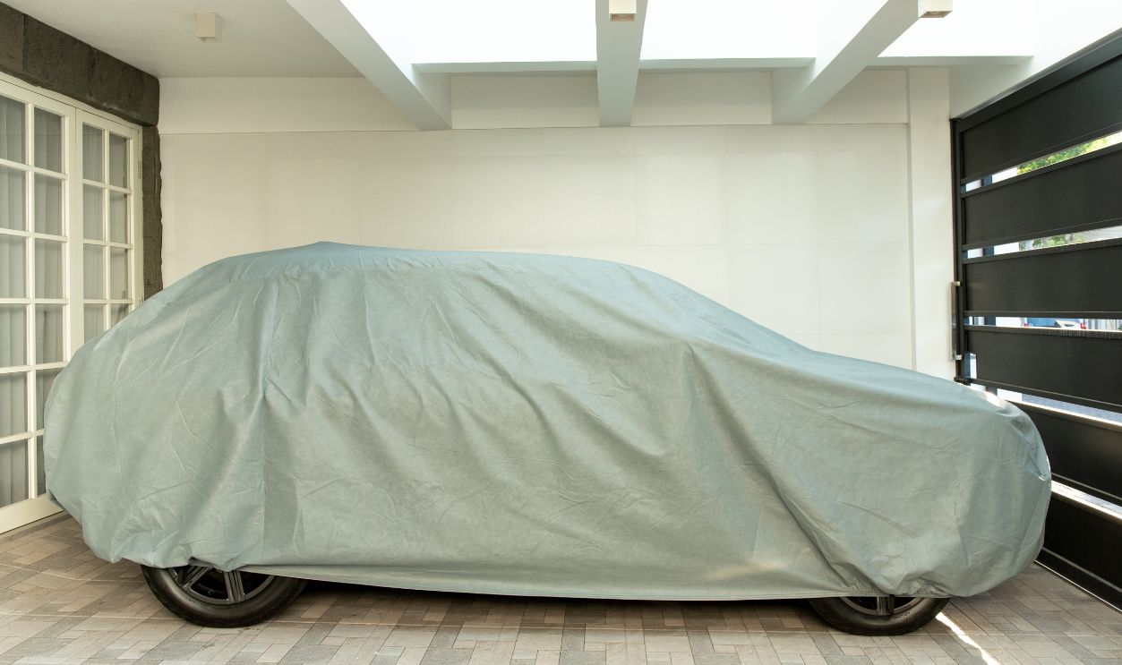 SUV car covered with a waterproof and dustproof cloth cover, parked in the garage of the house