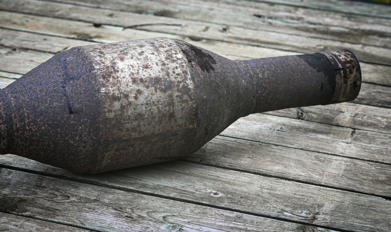 a used automotive catalytic converter. on a wood background. rustic auto parts design element