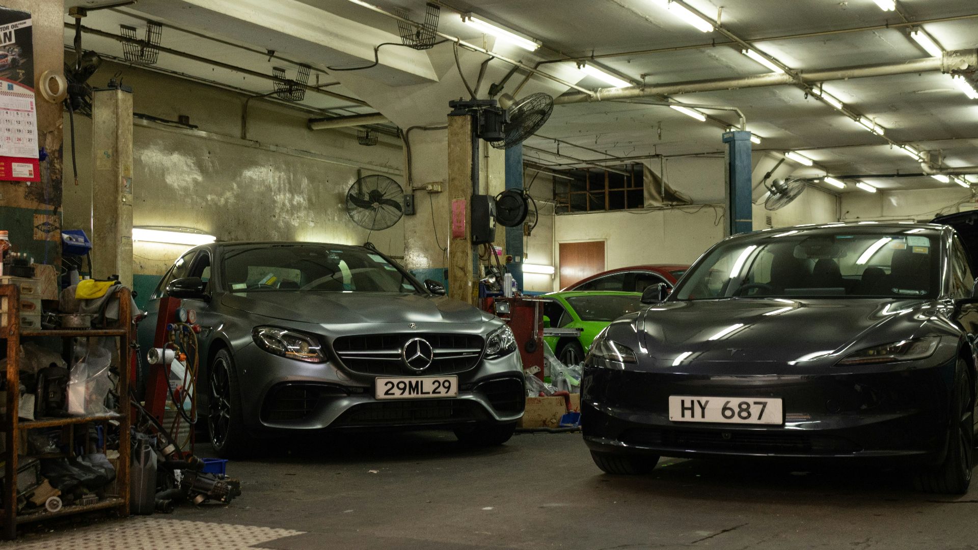 Two luxury cars parked inside a dimly lit industrial automotive repair garage