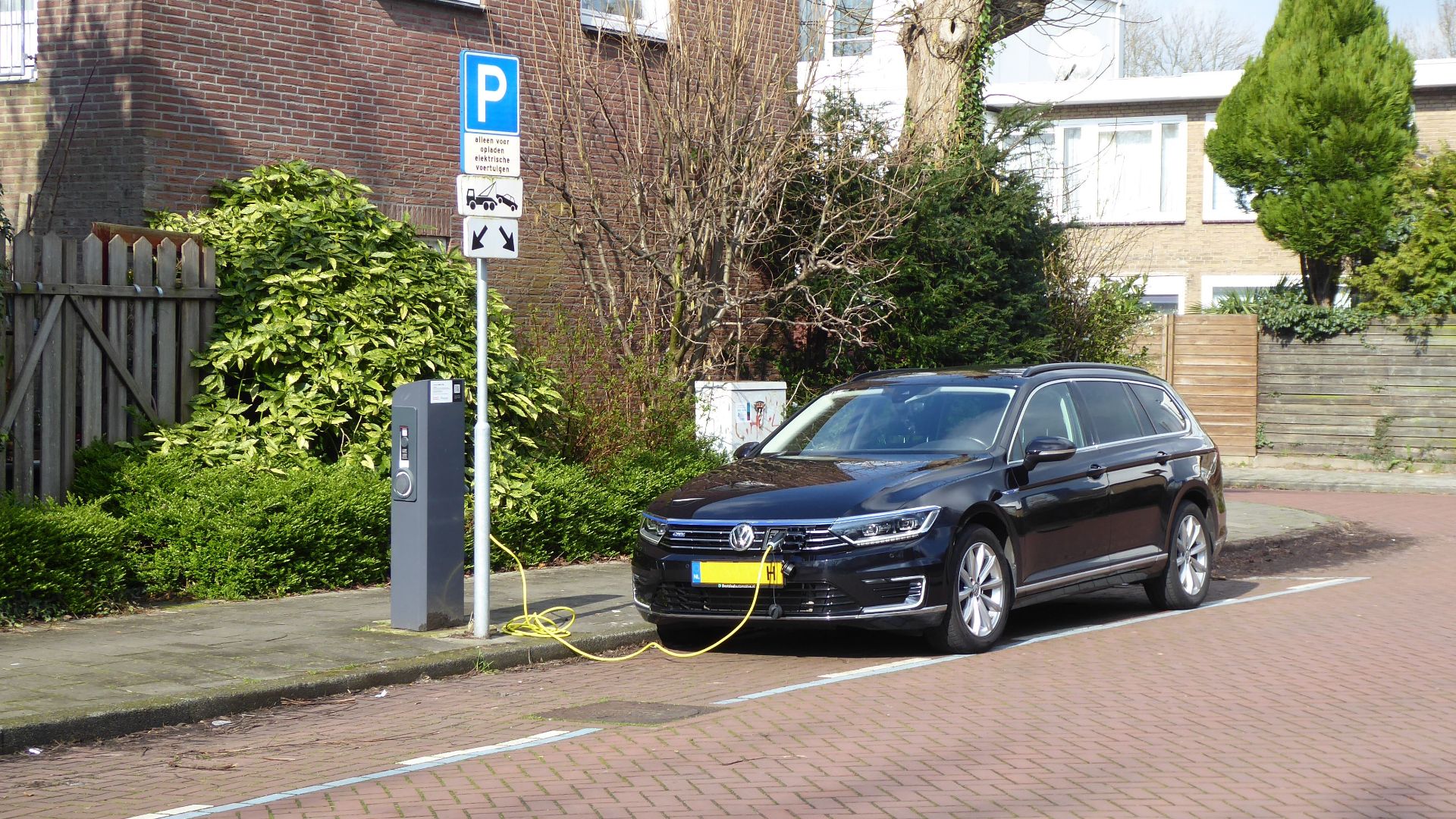 Electric car charging at a street station in Amsterdam, highlighting urban eco-friendliness.