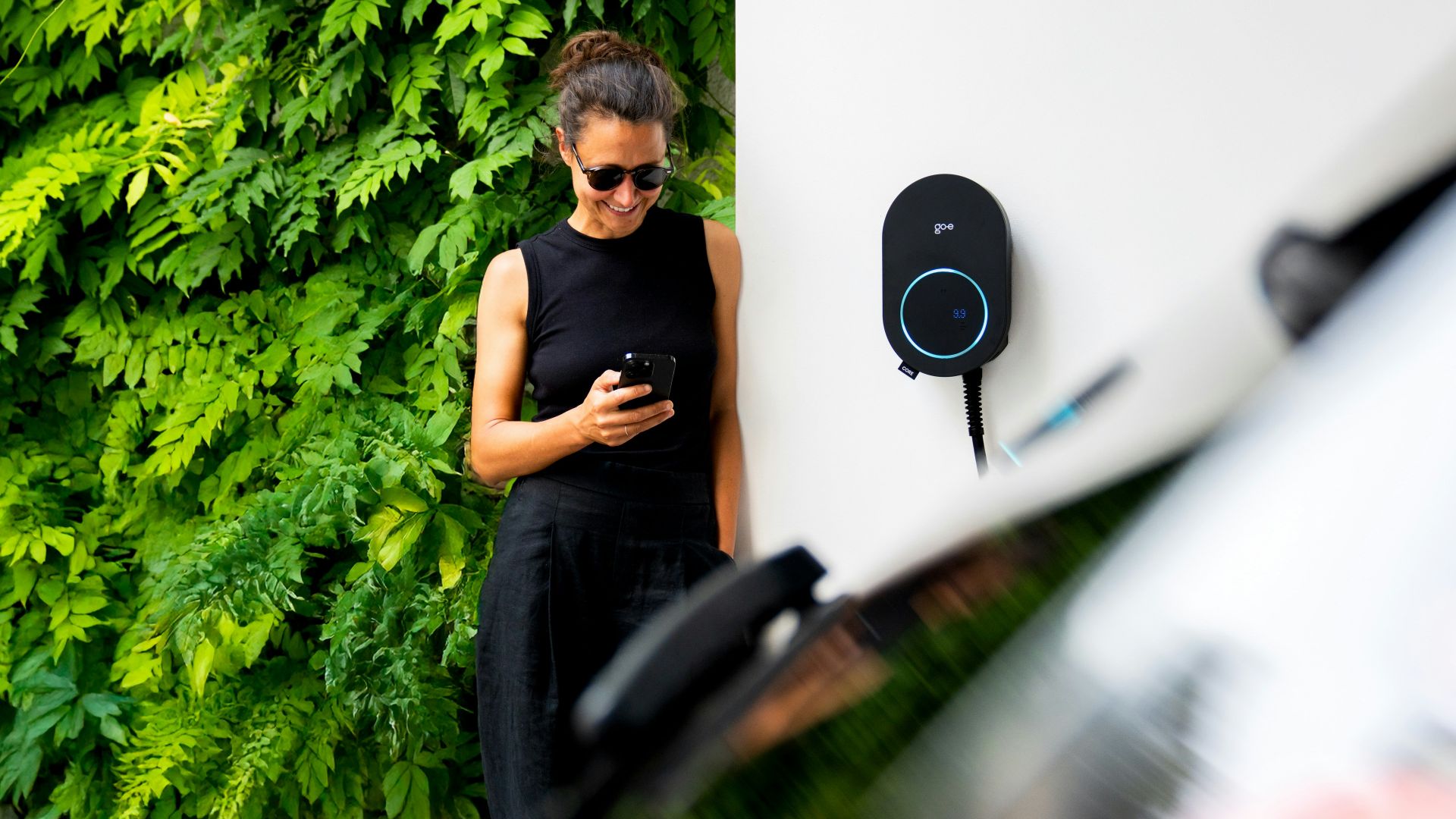 Woman using phone near electric car charger