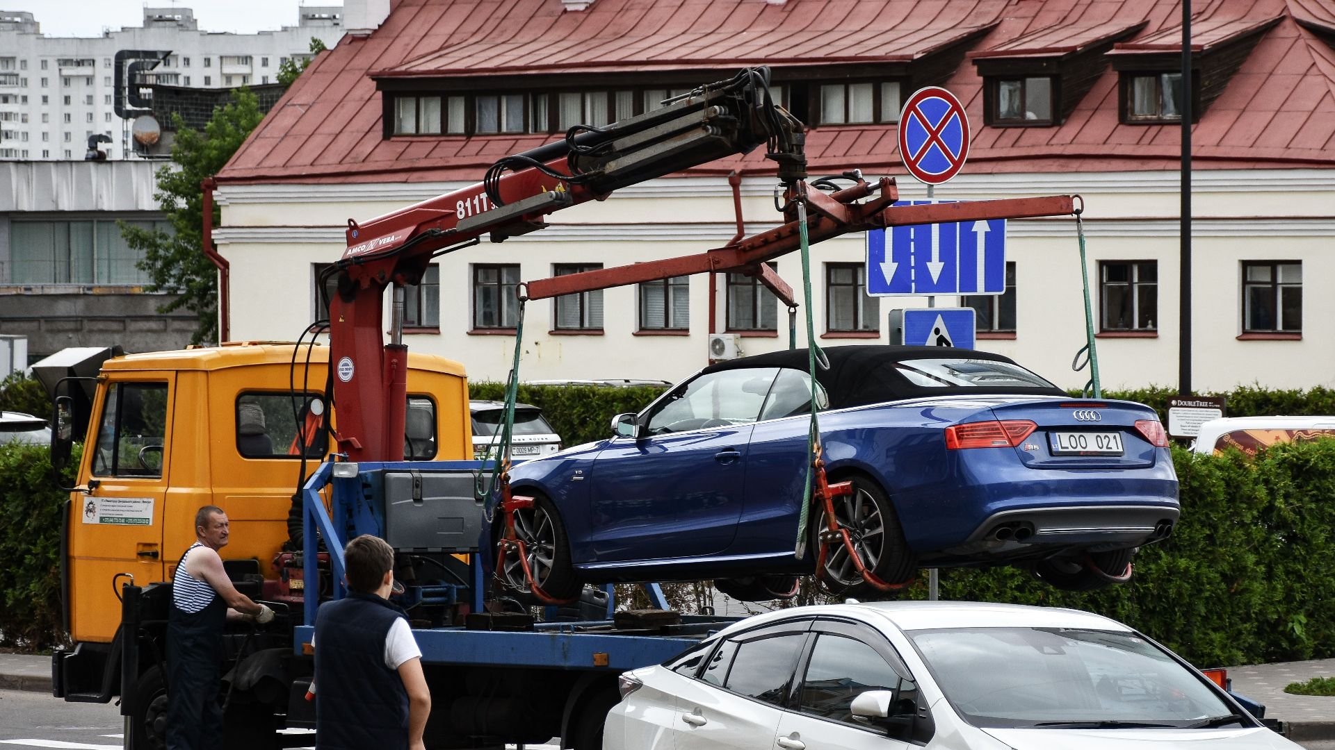 Towing a blue Audi convertible in a bustling city street.