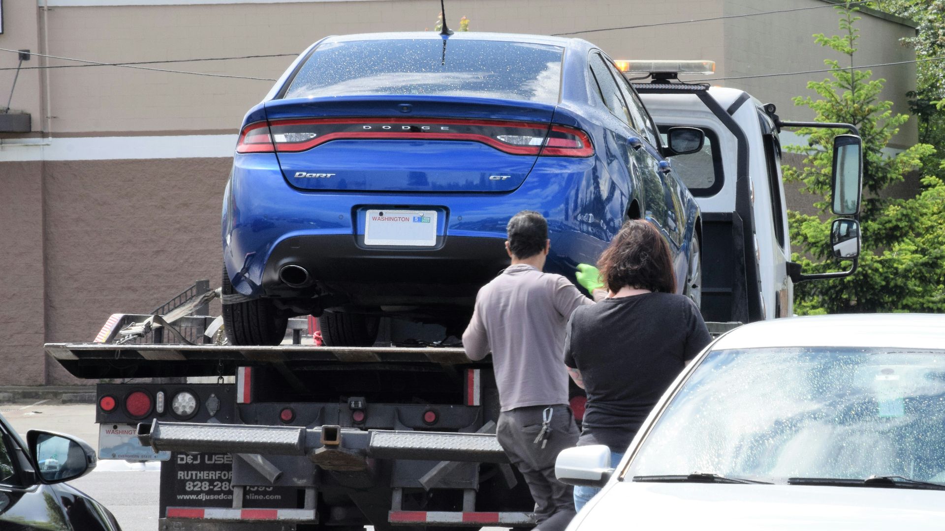 a blue car being loaded onto a flatbed truck