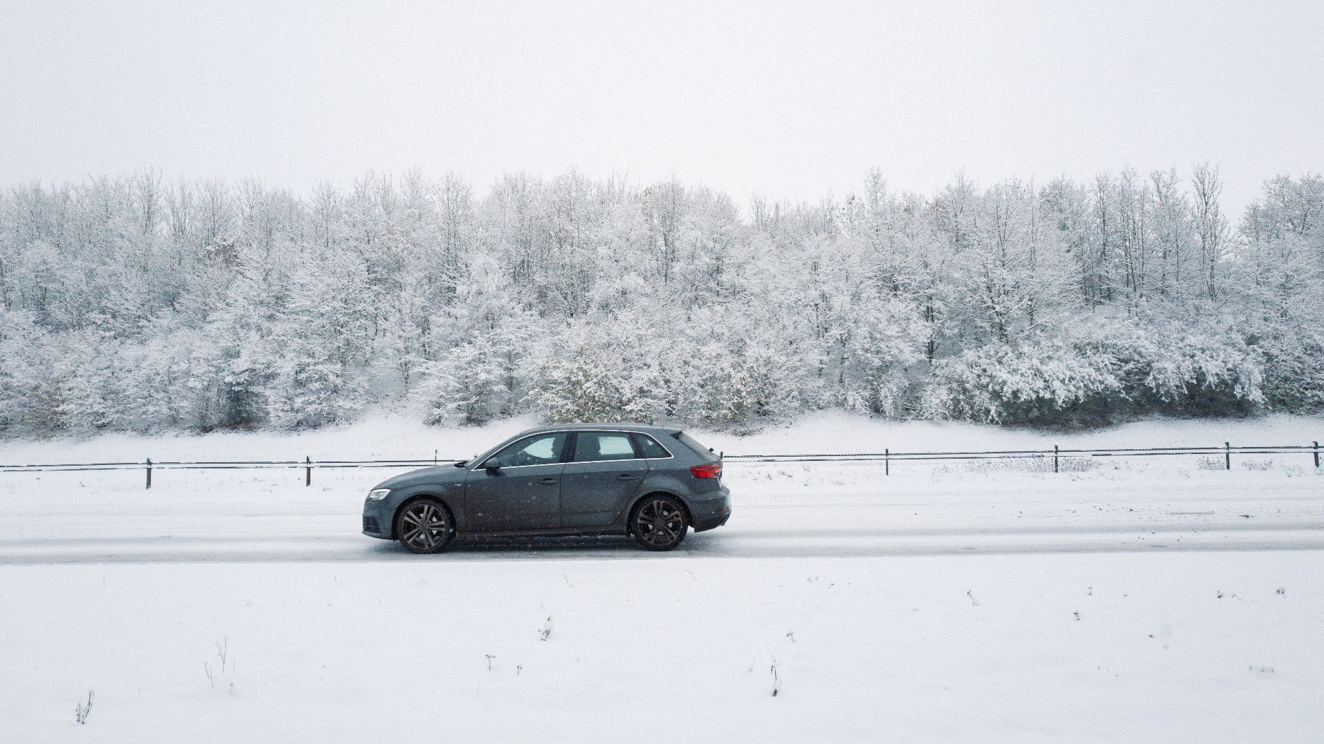 a car driving on a snowy road near a forest