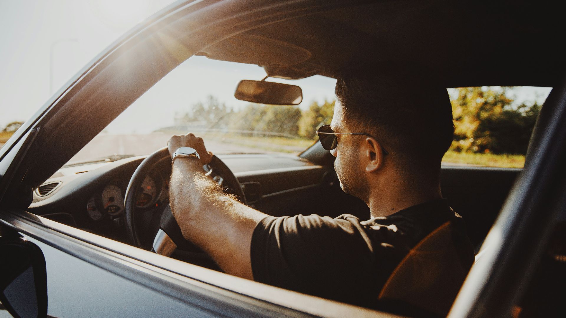 man in black jacket driving car during daytime