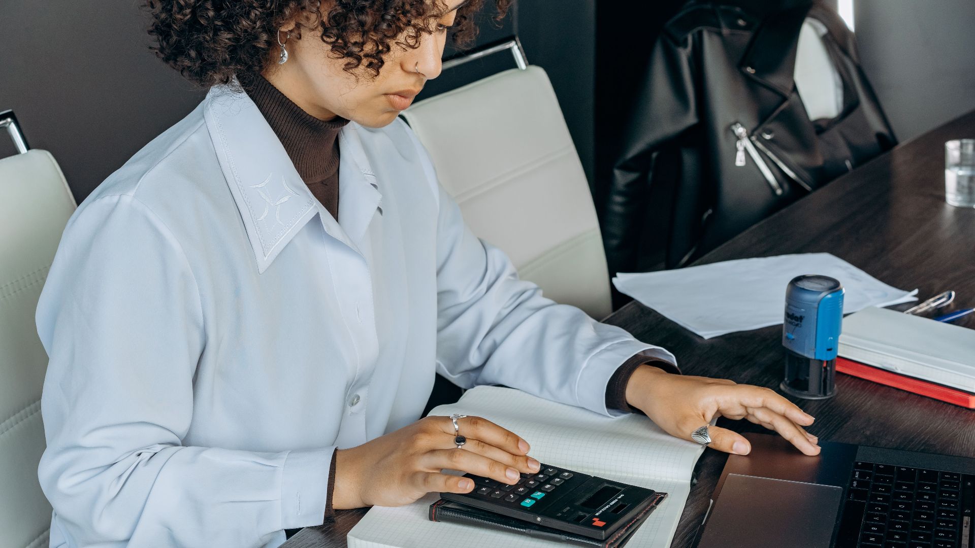 Young woman in office using a calculator for financial calculations.