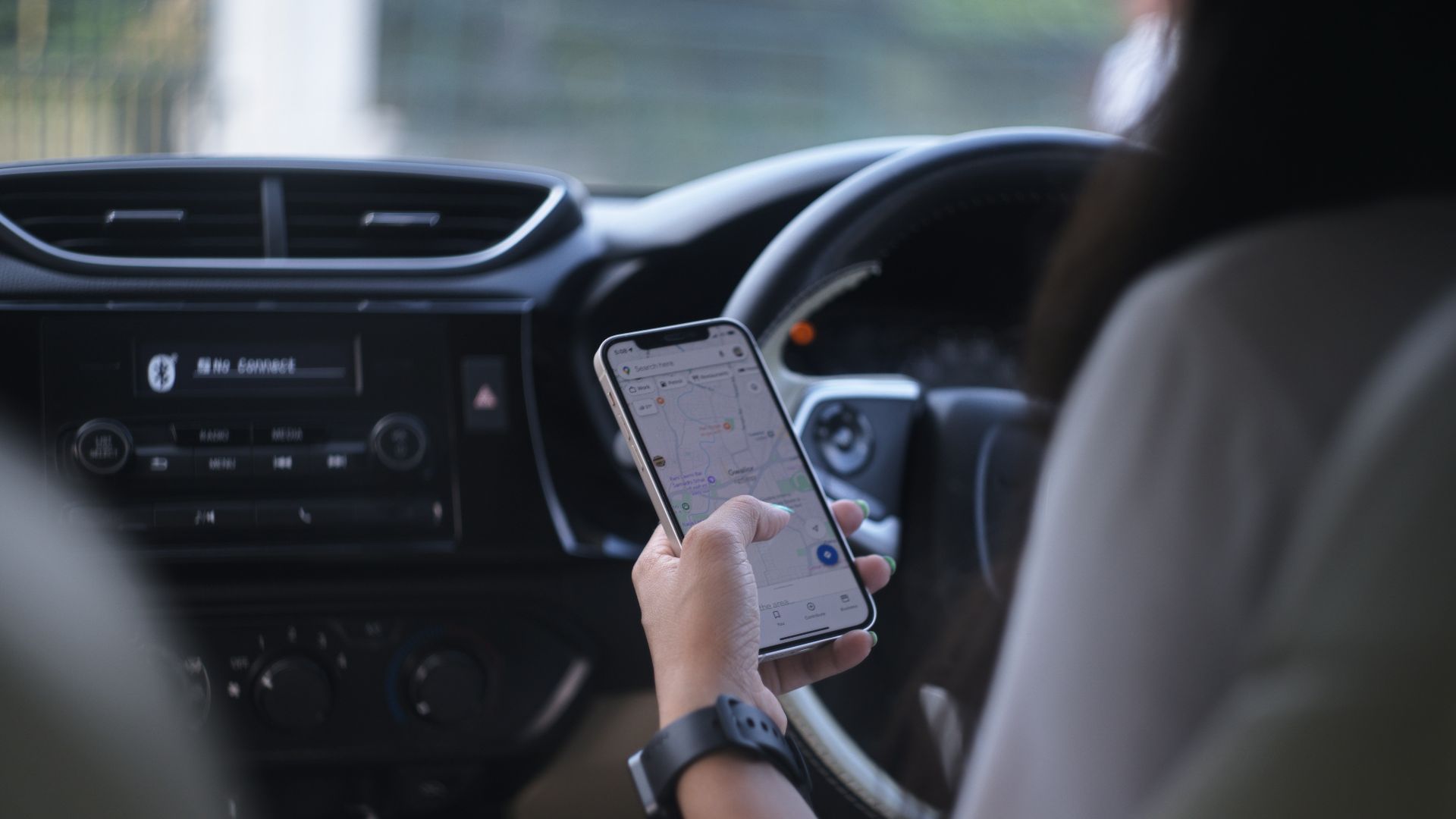A woman holding a cell phone while driving a car