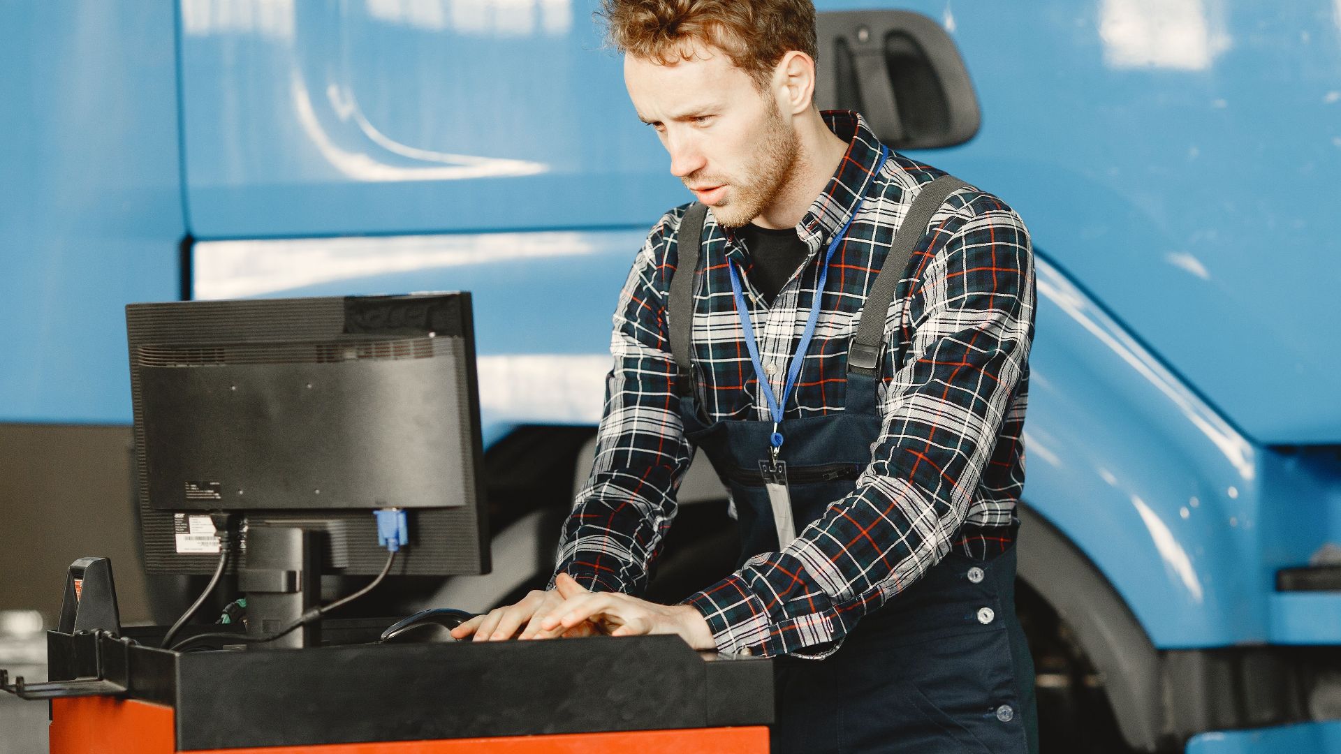 Auto mechanic in a workshop using a computer to diagnose a vehicle.