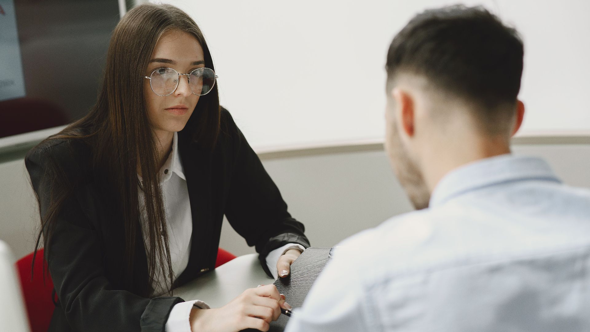 Two professionals engage in a serious business meeting at a modern office setting.