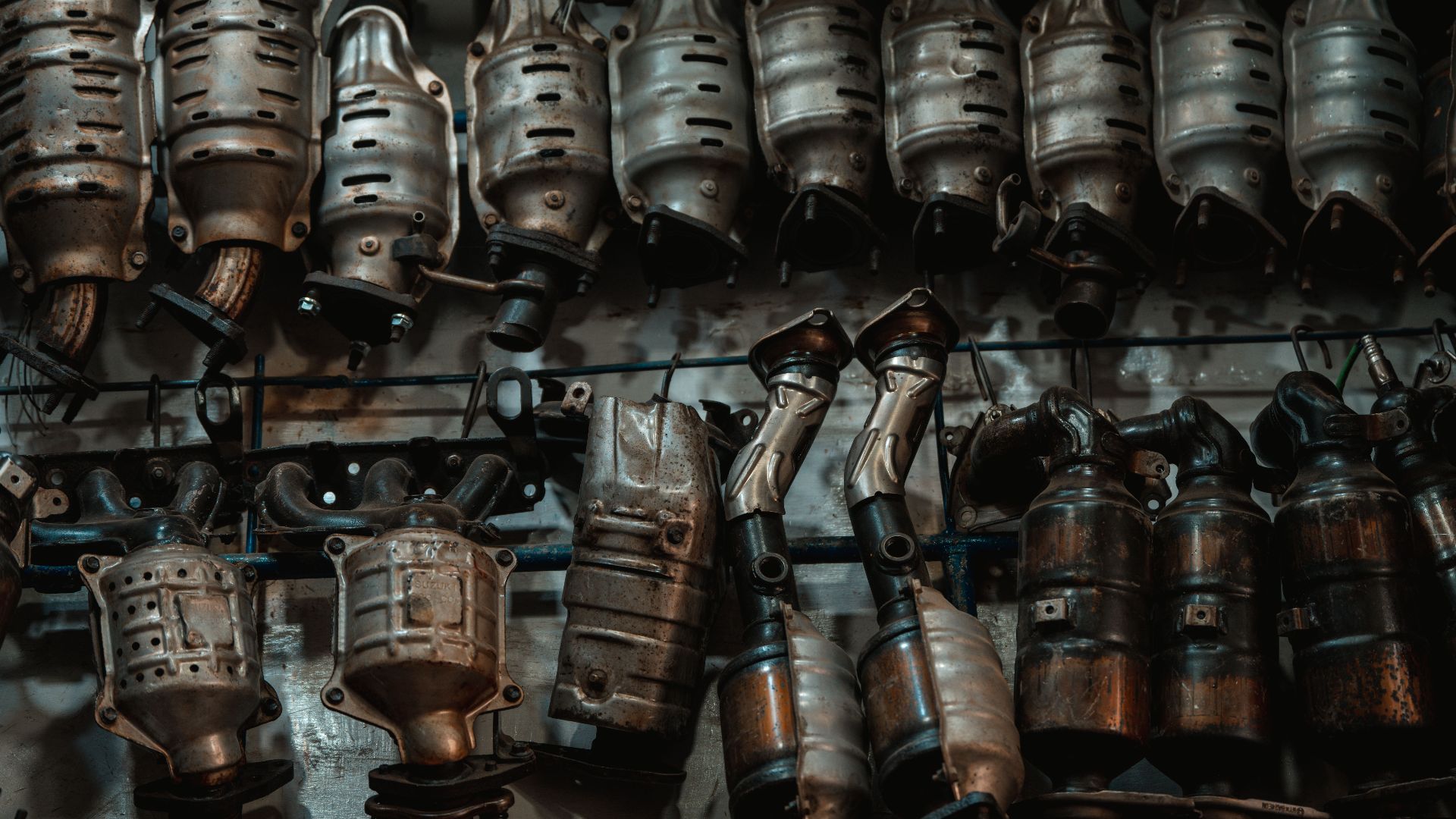 Rows of used catalytic converters in an automotive workshop setting.