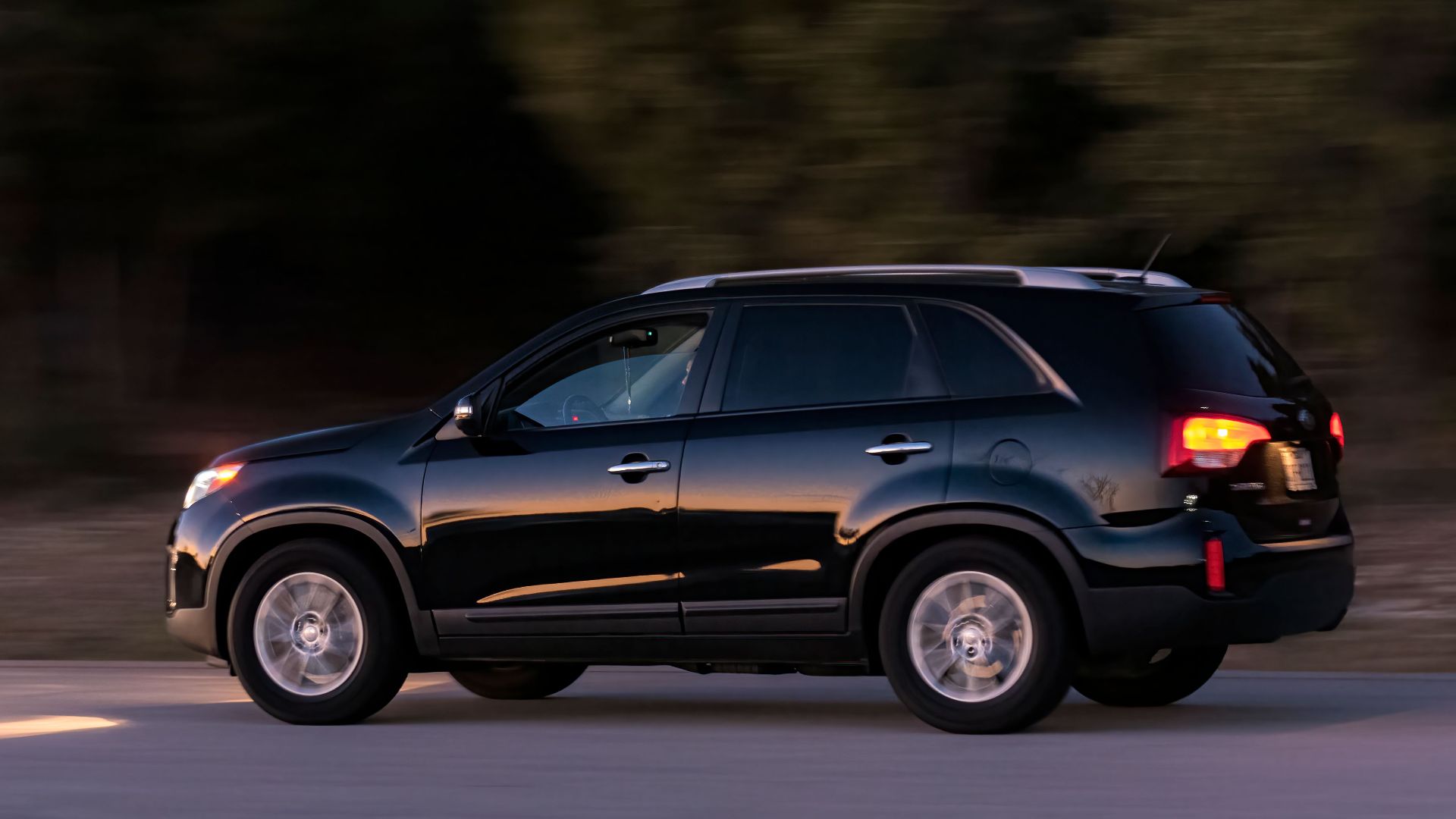 A black SUV captured in motion blur on a road, showcasing speed and elegance.