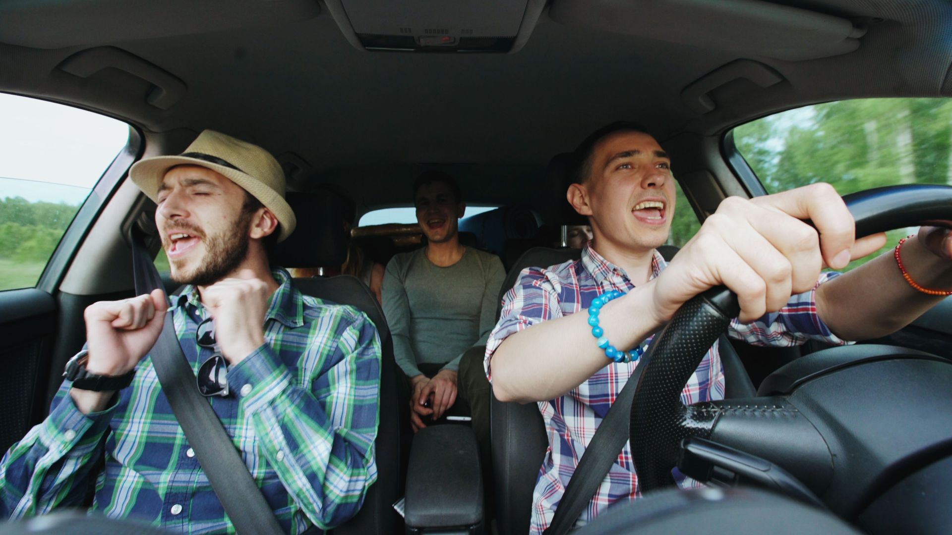 Three friends singing joyfully during a road trip, highlighting fun travel moments.