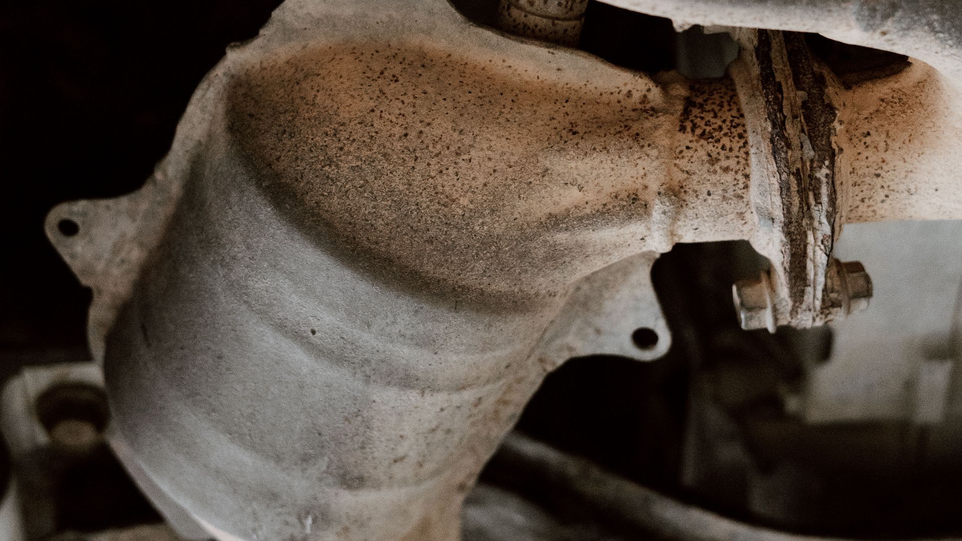 Detailed close-up of rusted exhaust system parts under a vehicle.