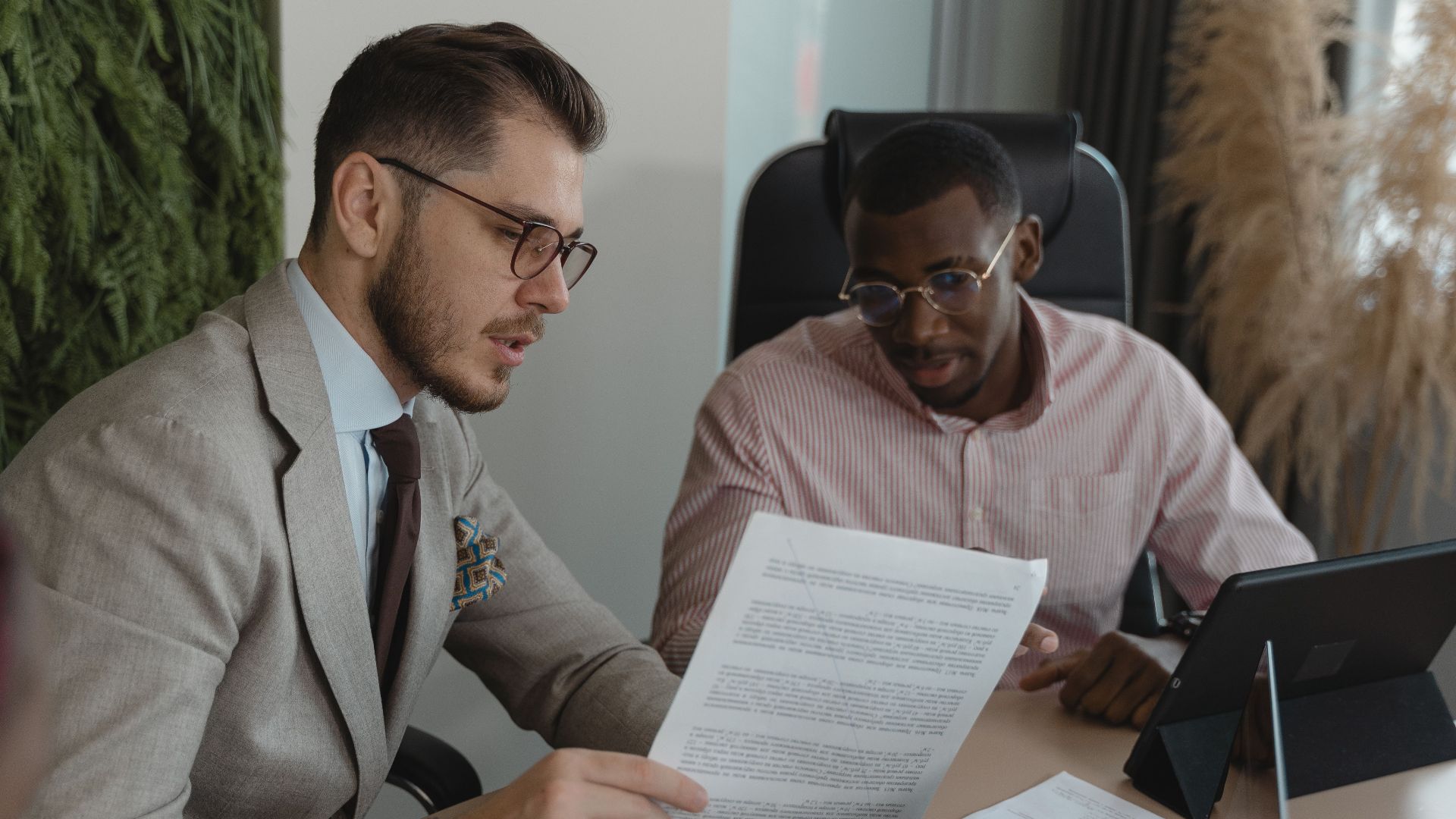 Two businessmen in an office discussing documents and working together.