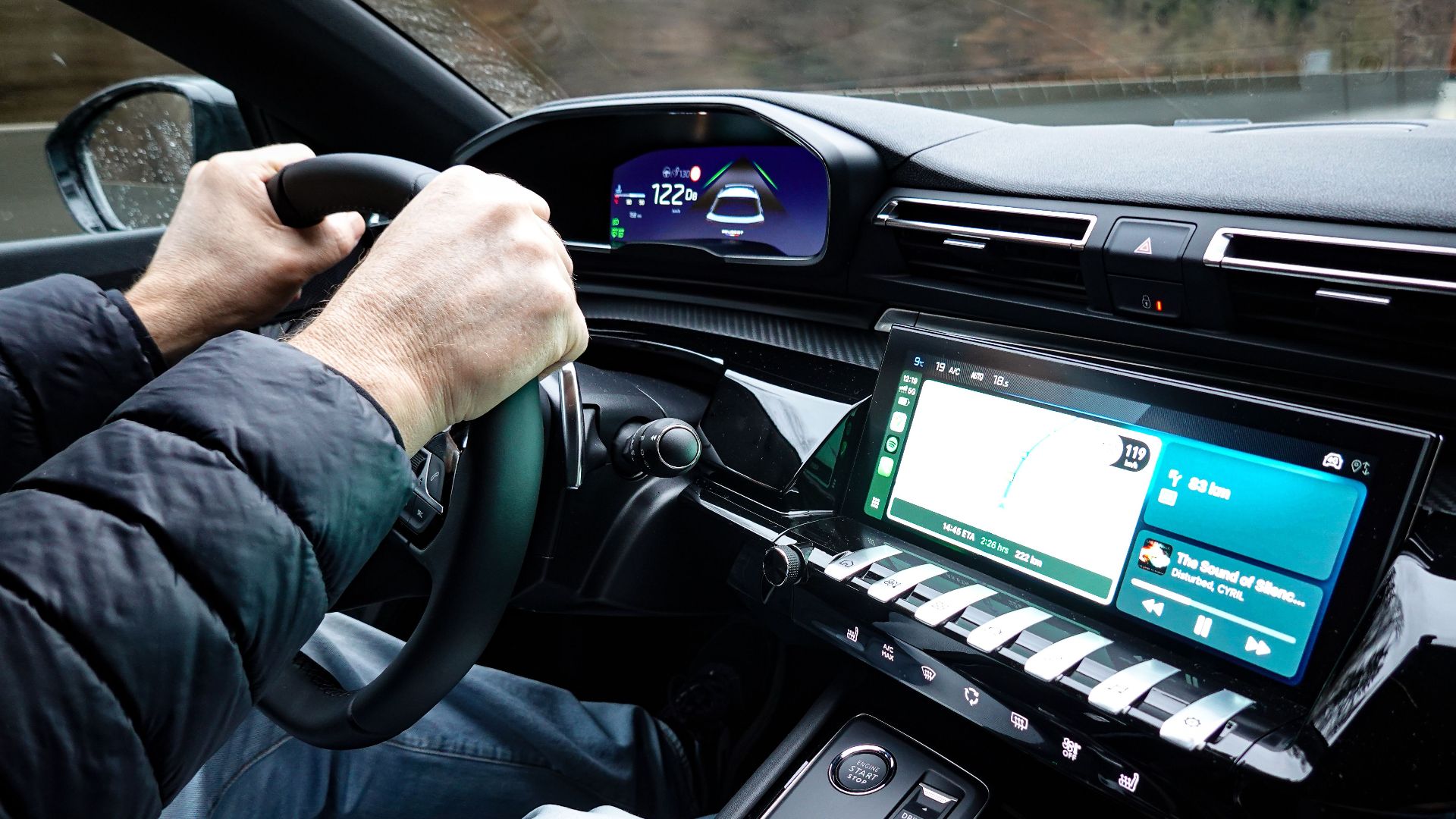 A detailed view of a car's interior with hands on the steering wheel, showcasing modern technology.