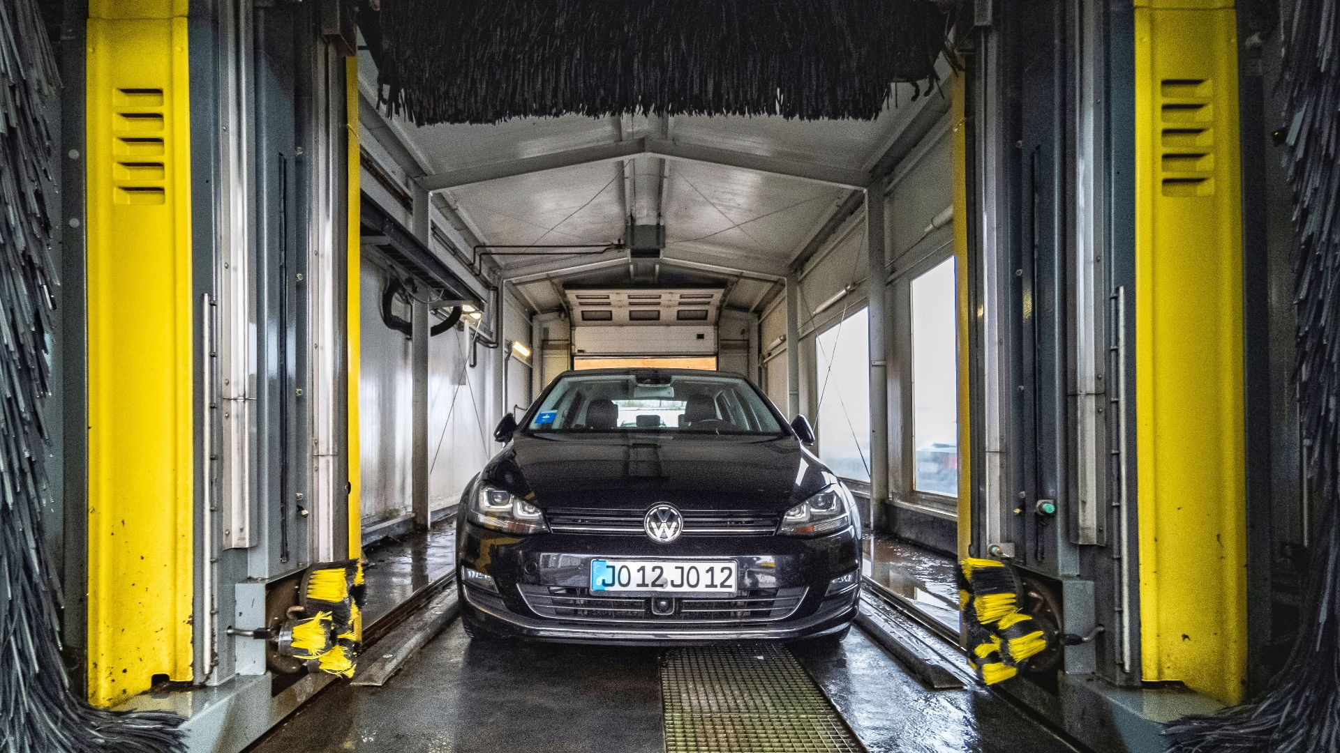 A black car undergoing a thorough cleaning in an automated car wash facility.