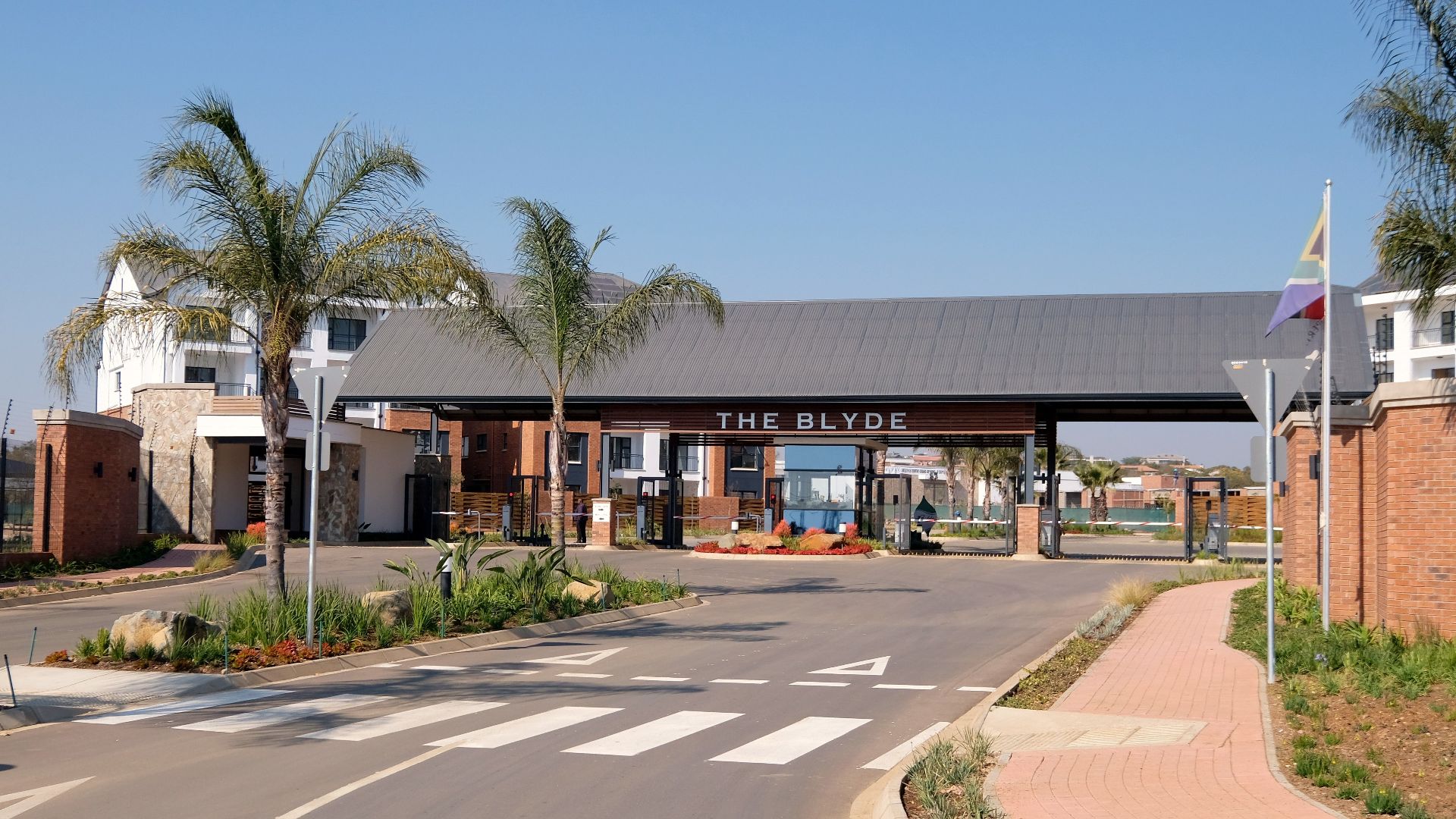 Entrance to The Blyde residential complex showcasing modern architecture and palm trees.