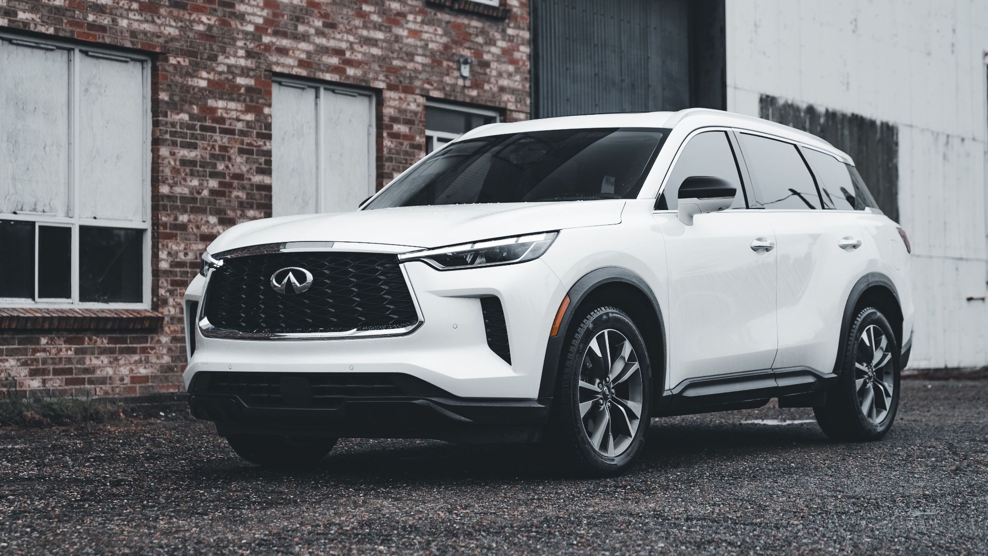 White luxury SUV parked outdoors in front of a brick building, showcasing modern automotive design.