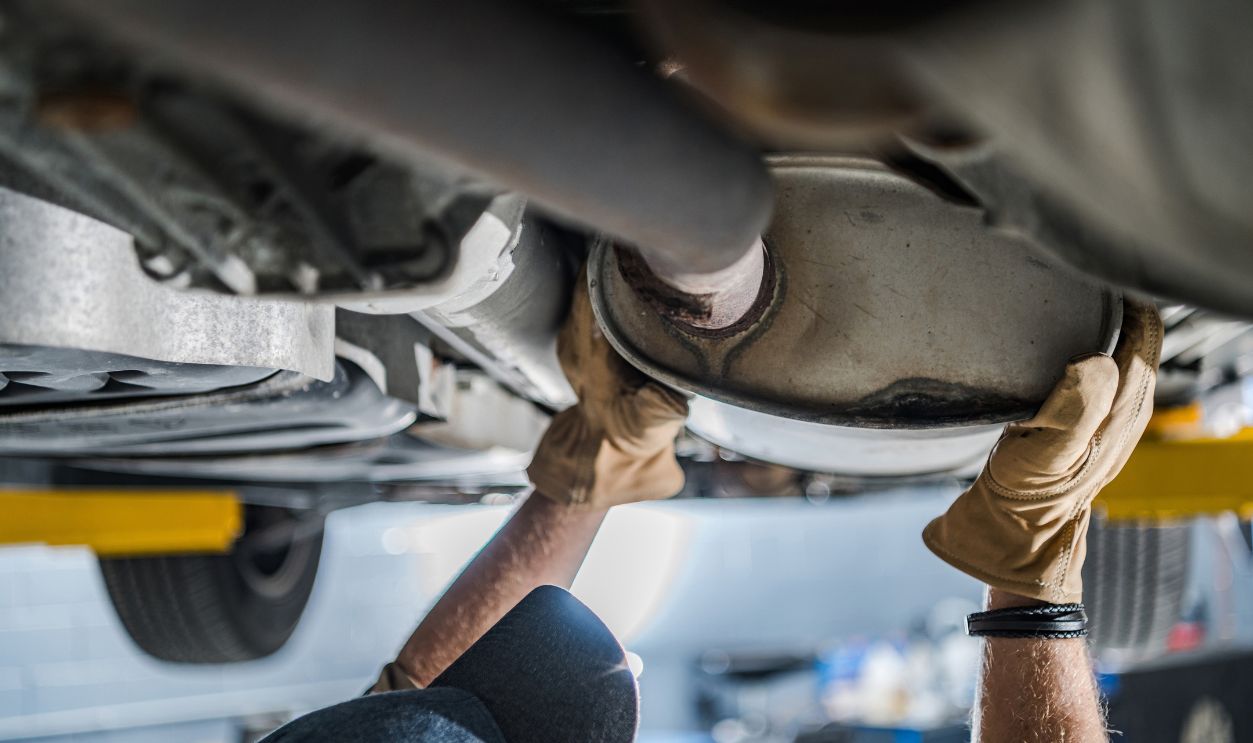 Mechanic Inspecting Vehicle's Catalytic Converter During Scheduled Car Exhaust System Check. Automobile Maintenance Theme.